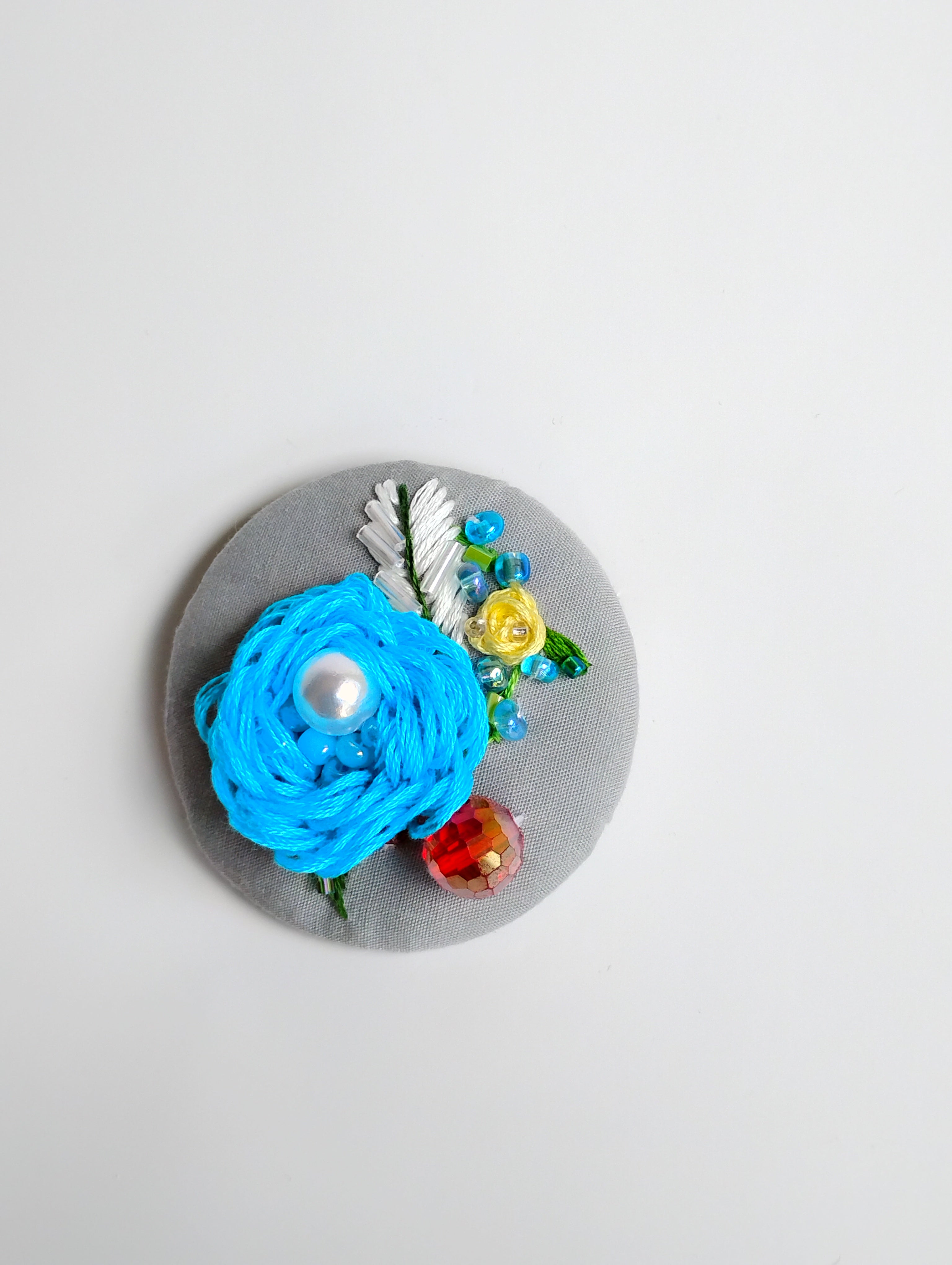 Decorative turquoise flower brooch on grey background