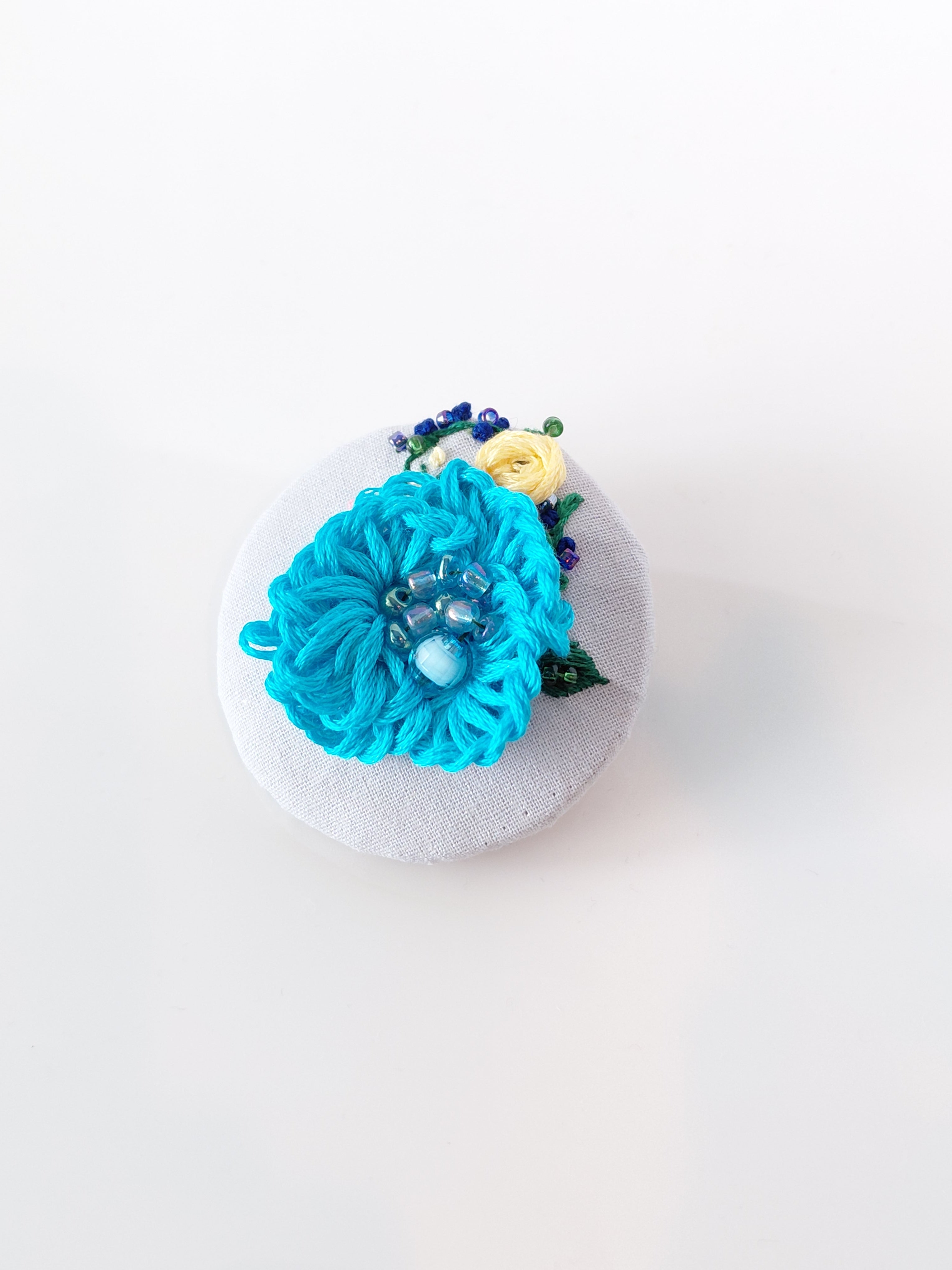 Decorative turquoise flower brooch on grey background