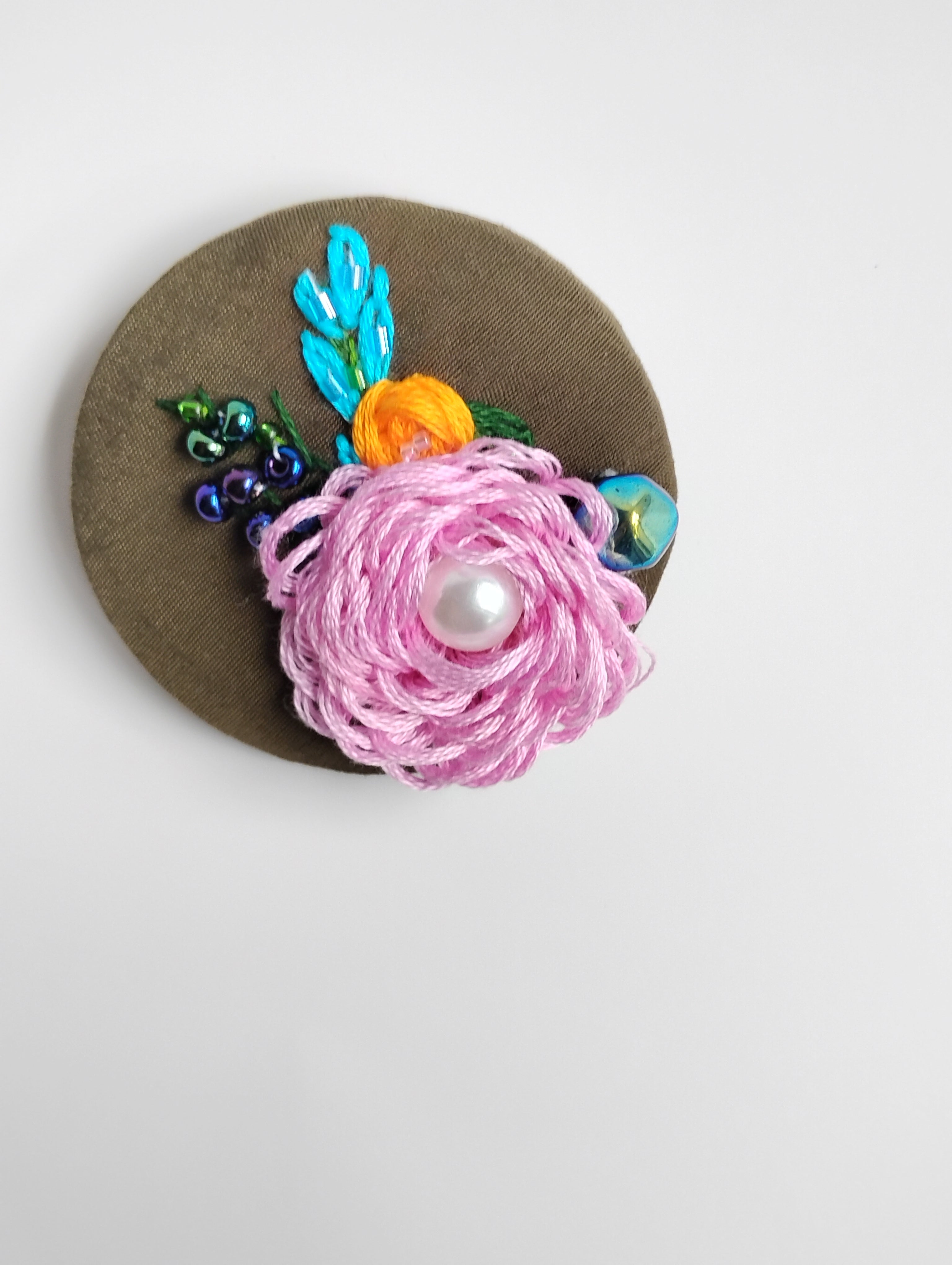 Decorative pink flower brooch on olive background