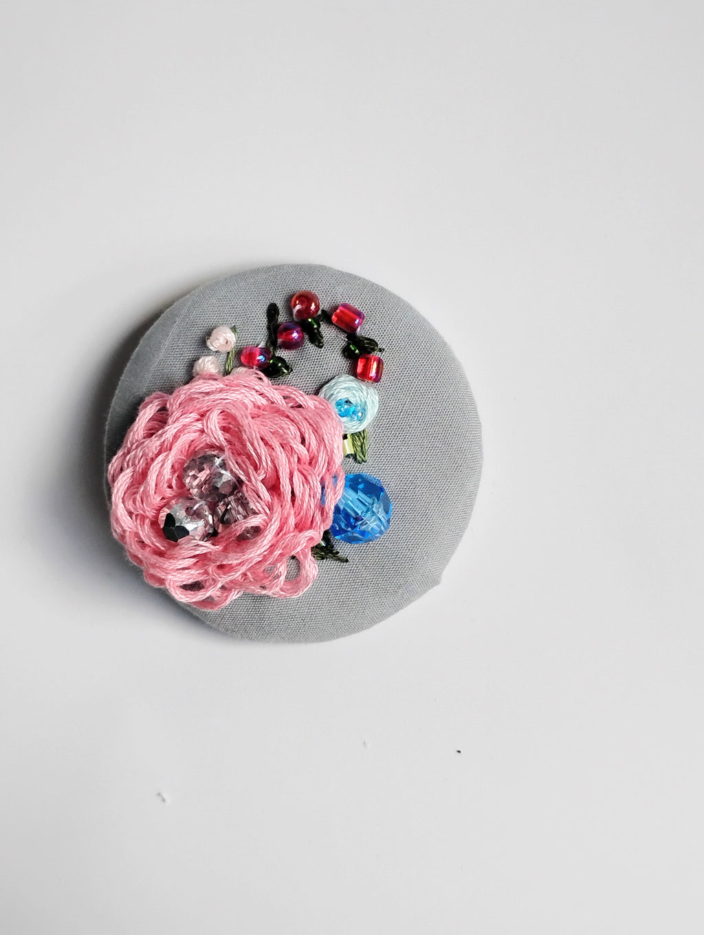 Decorative pink flower brooch on grey background