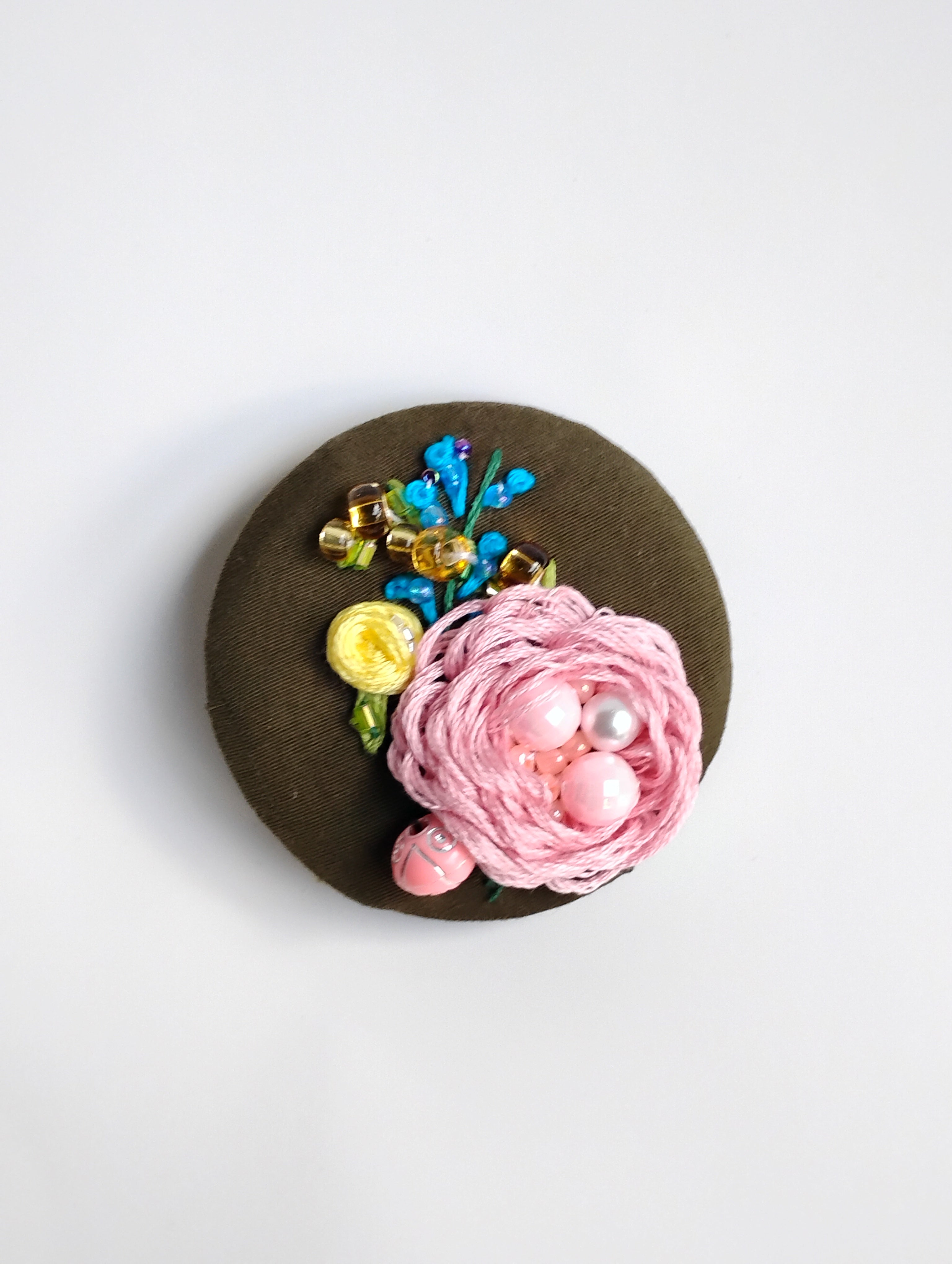 Decorative pink flower brooch on olive background