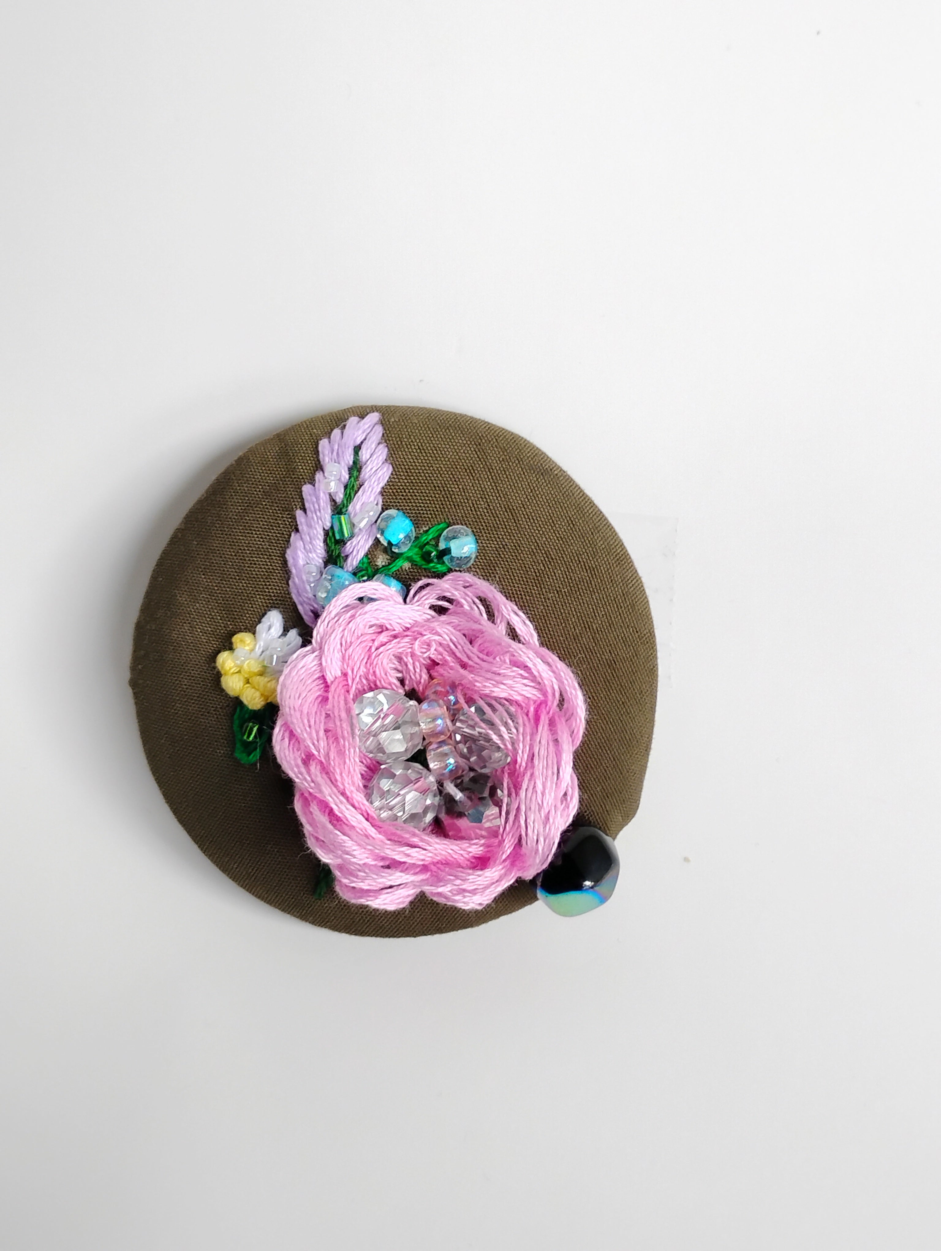 Decorative pink flower brooch on olive background