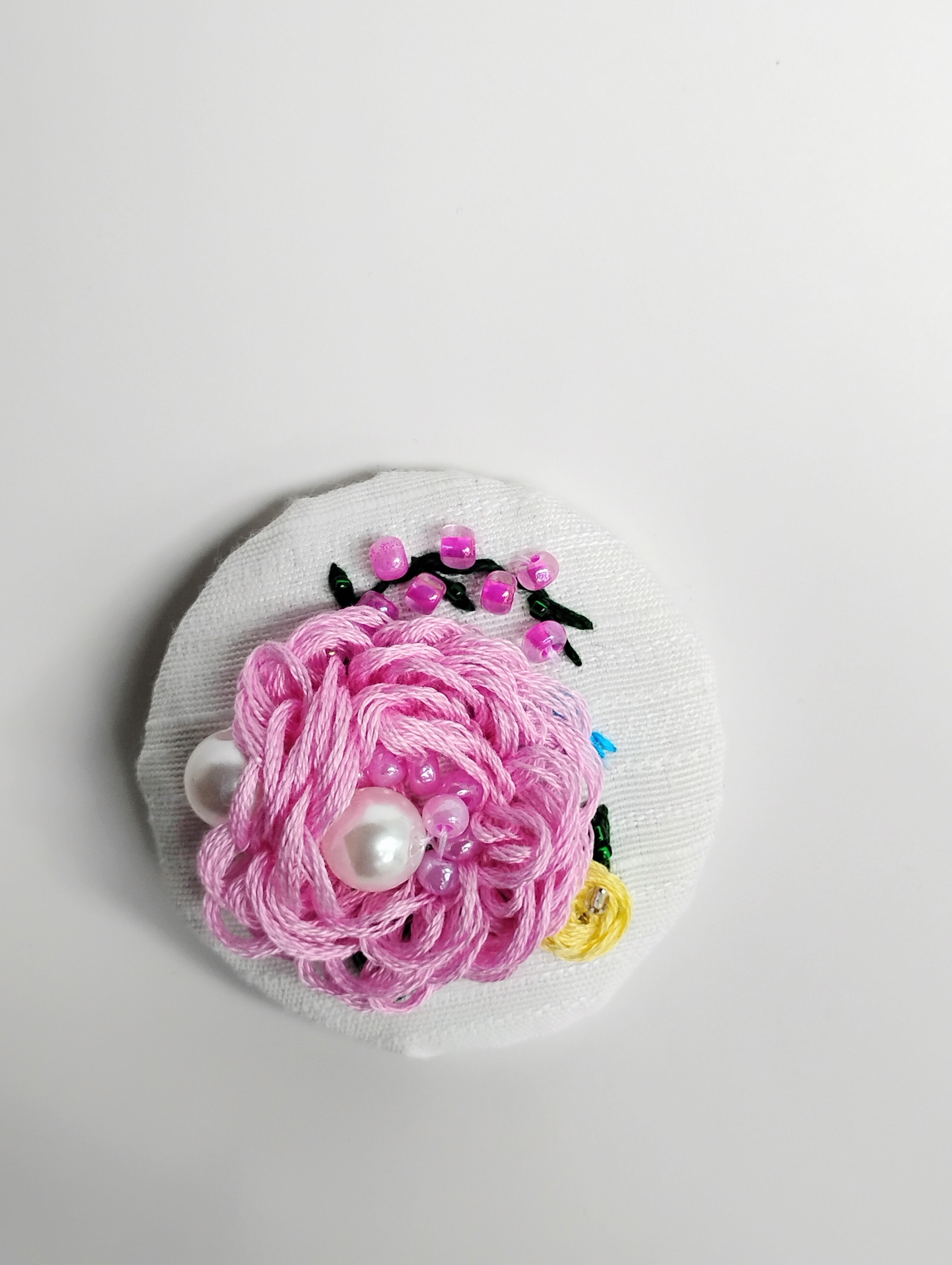 Decorative pink flower brooch on white textured background