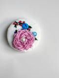 Decorative pink flower brooch on textured white background