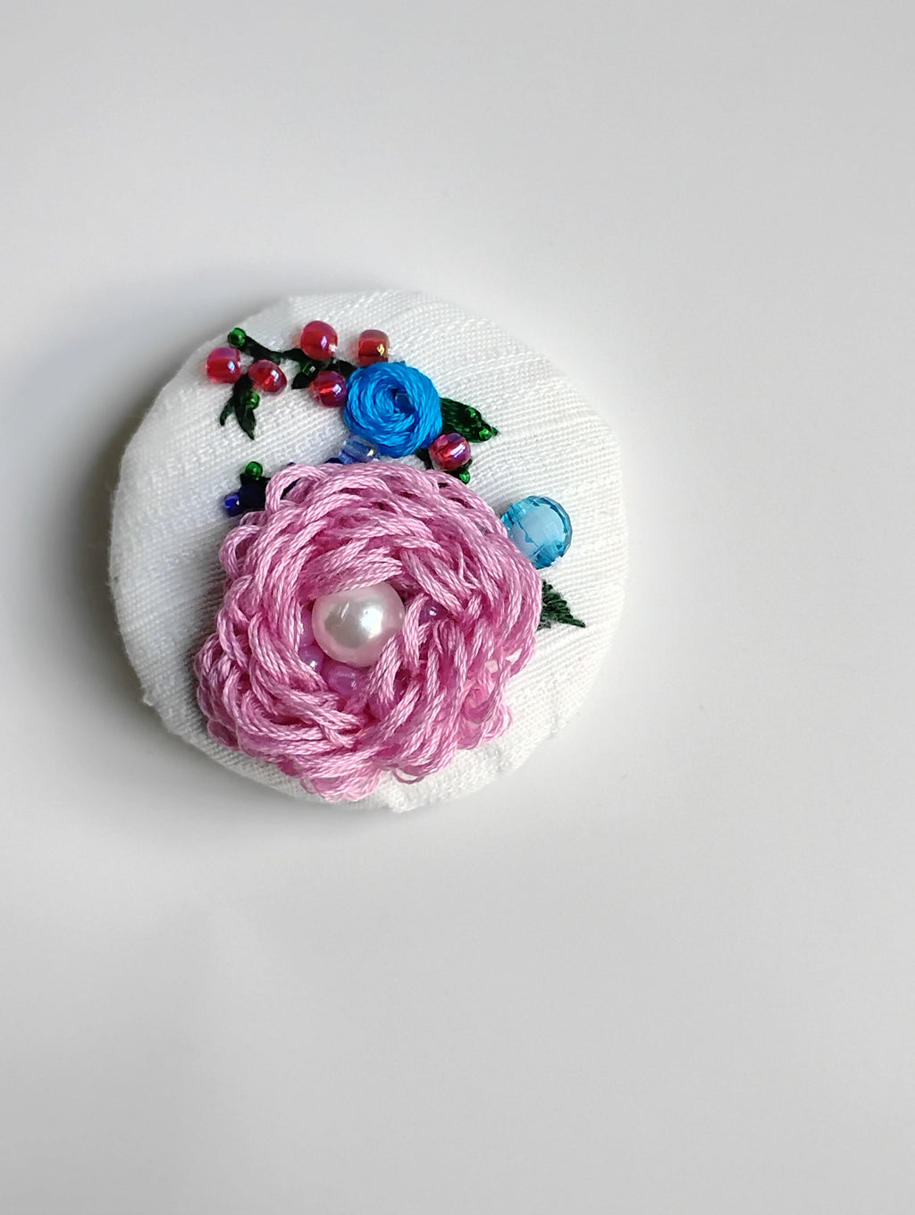 Decorative pink flower brooch on textured white background