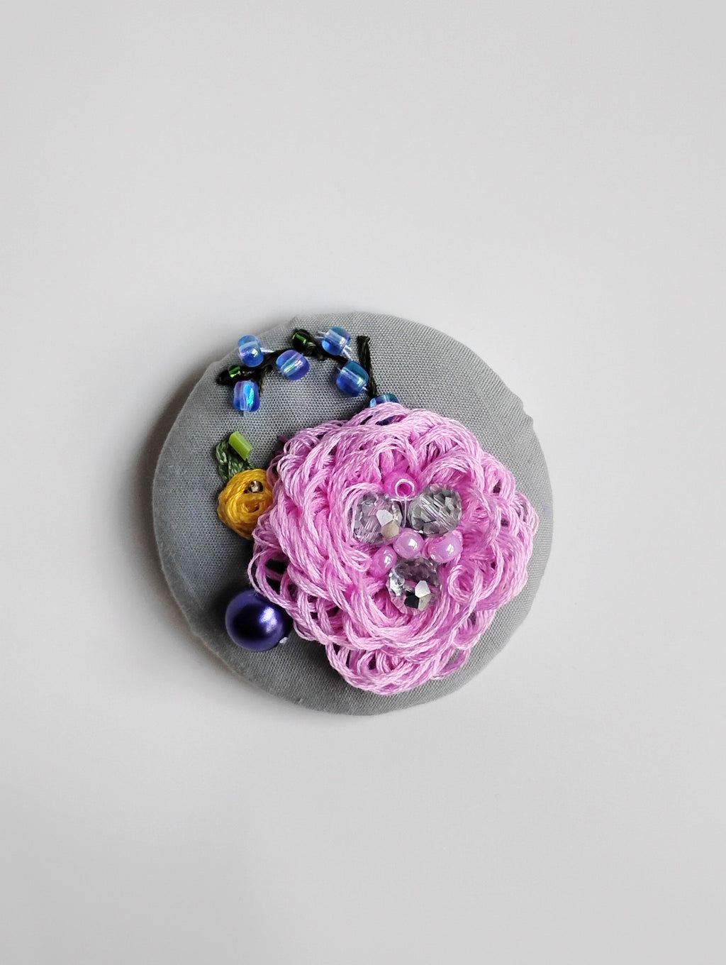 Decorative pink flower brooch on grey background
