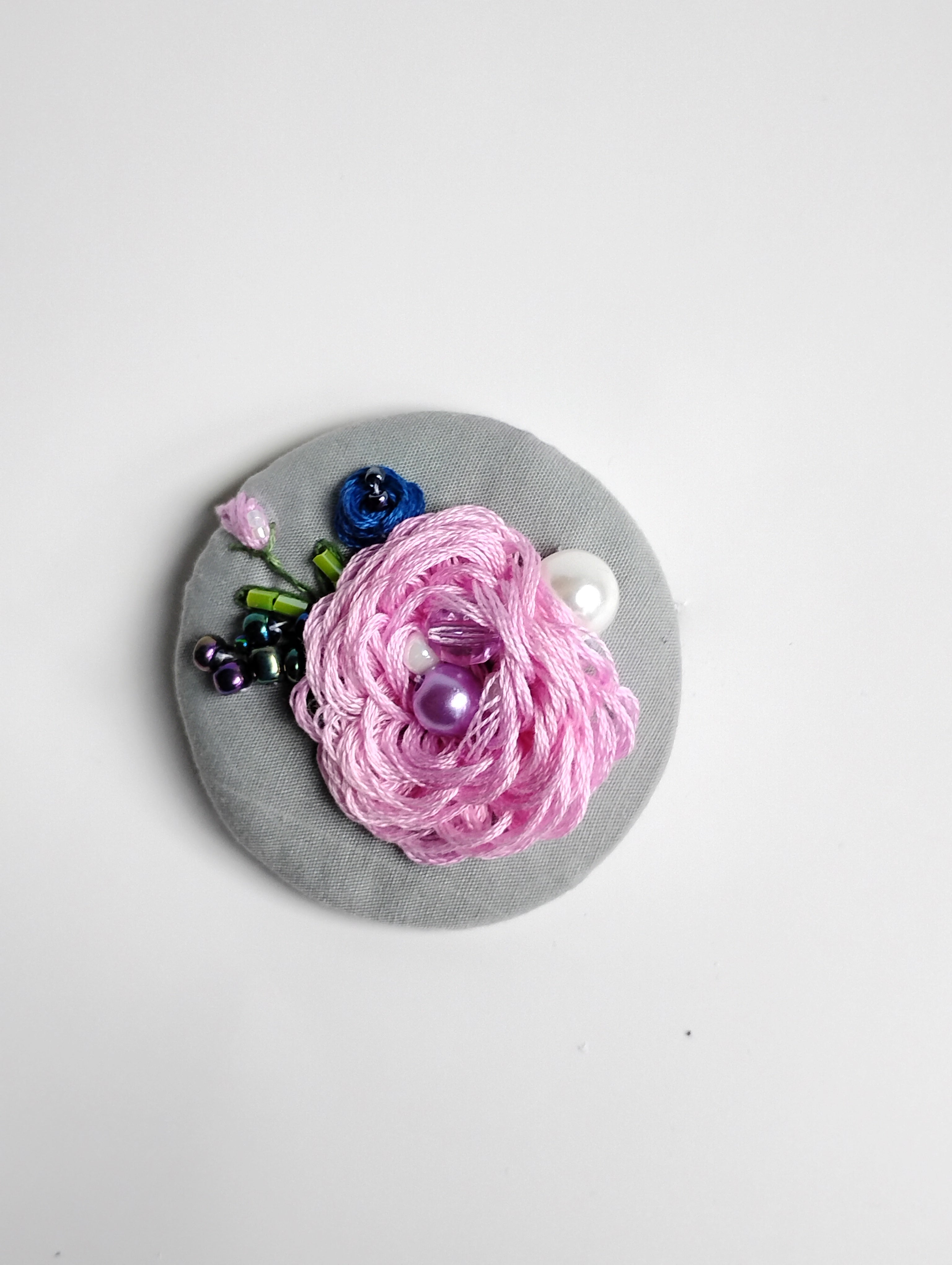 Decorative pink flower brooch on grey background