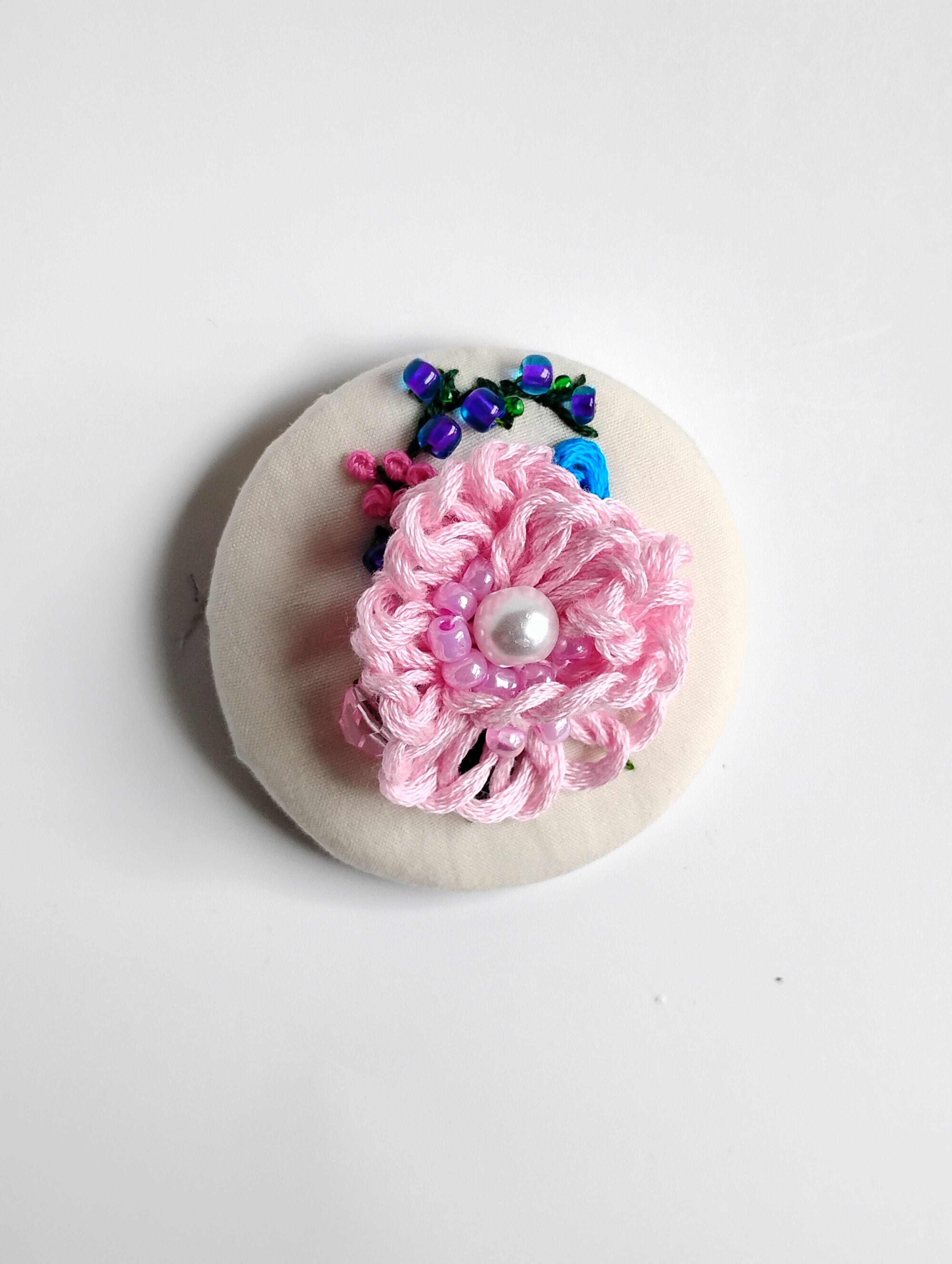 Decorative pink flower brooch on cream background