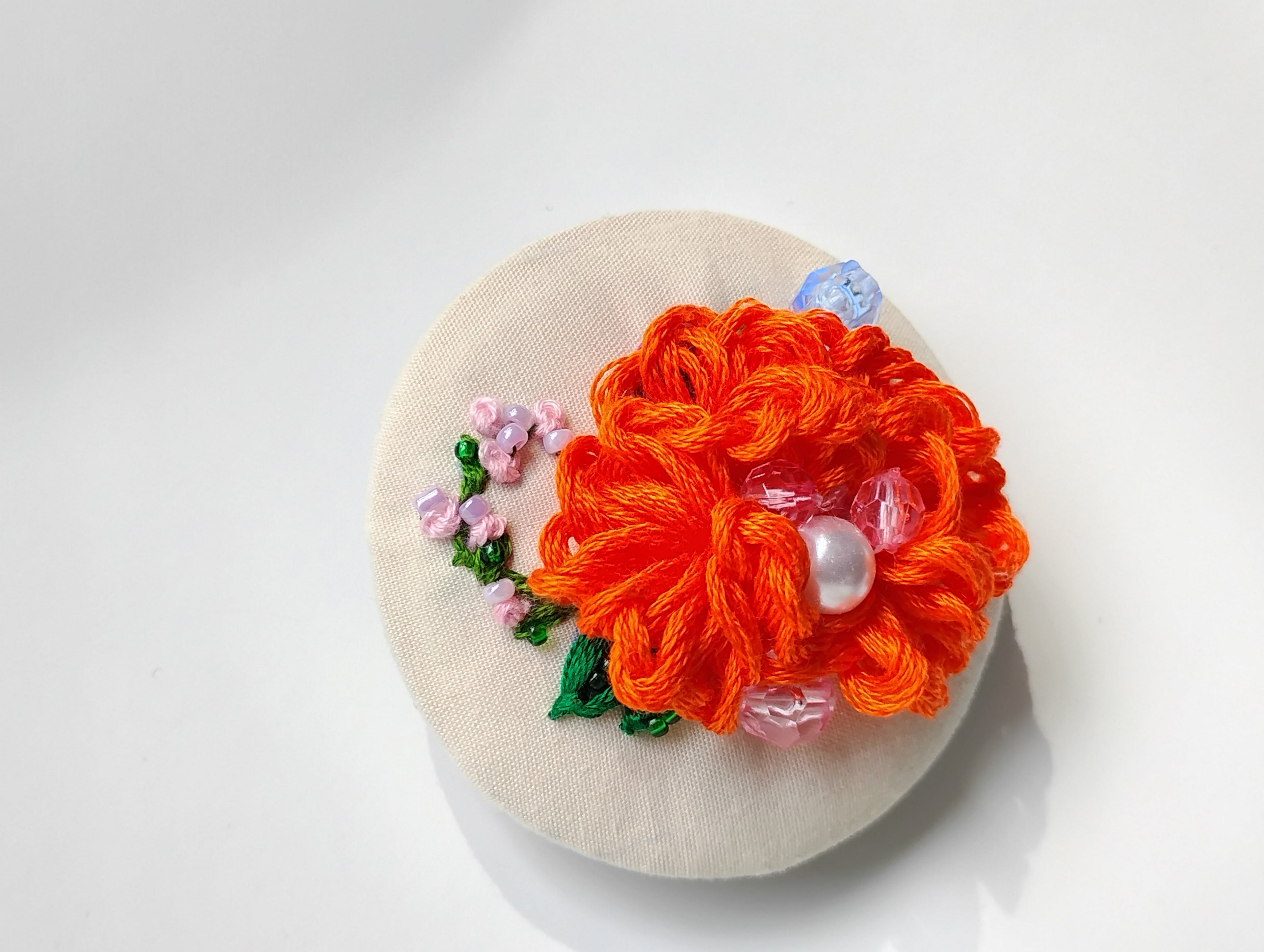 Decorative orange flower brooch on cream background