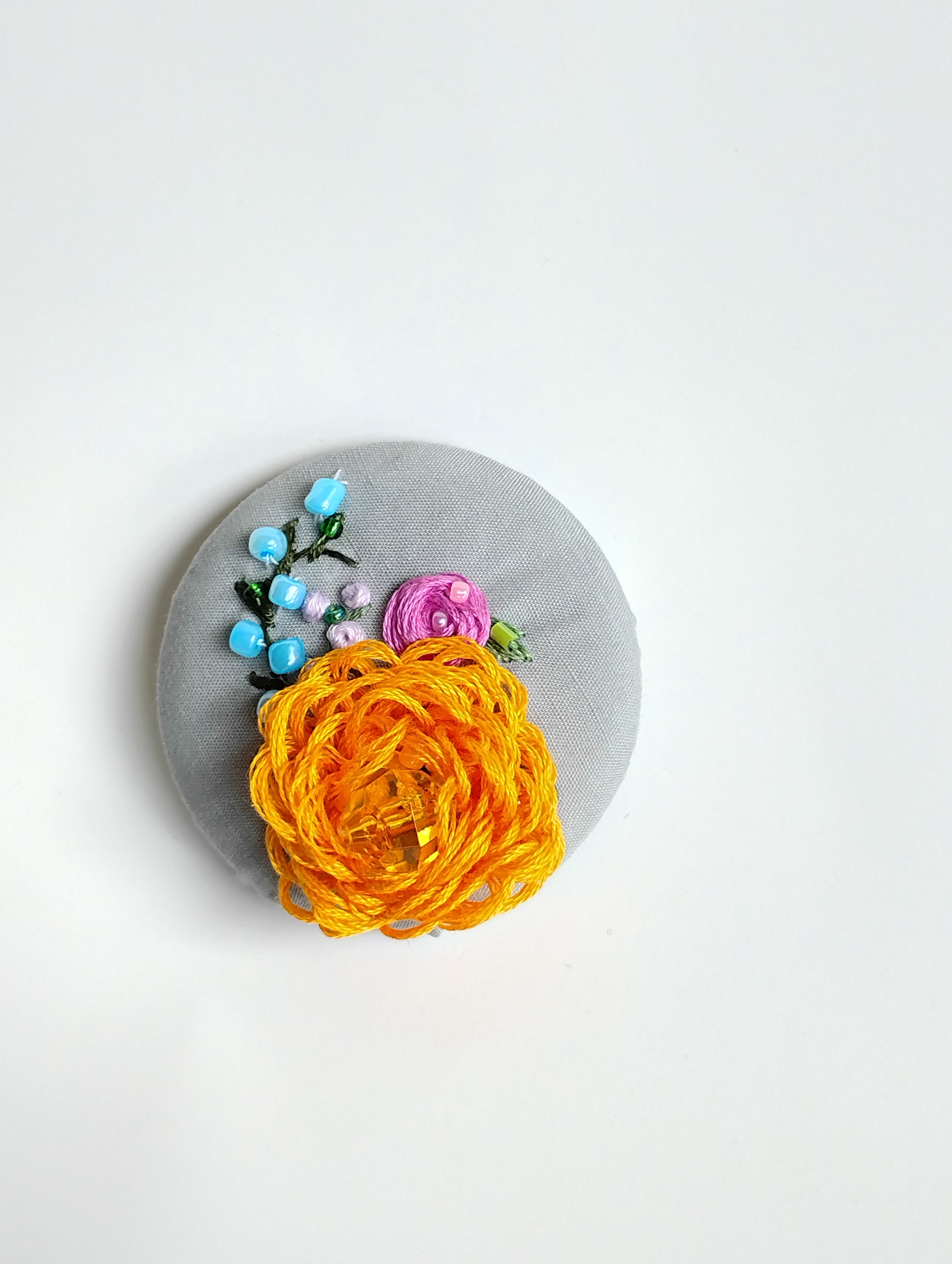 Decorative orange flower brooch on grey background