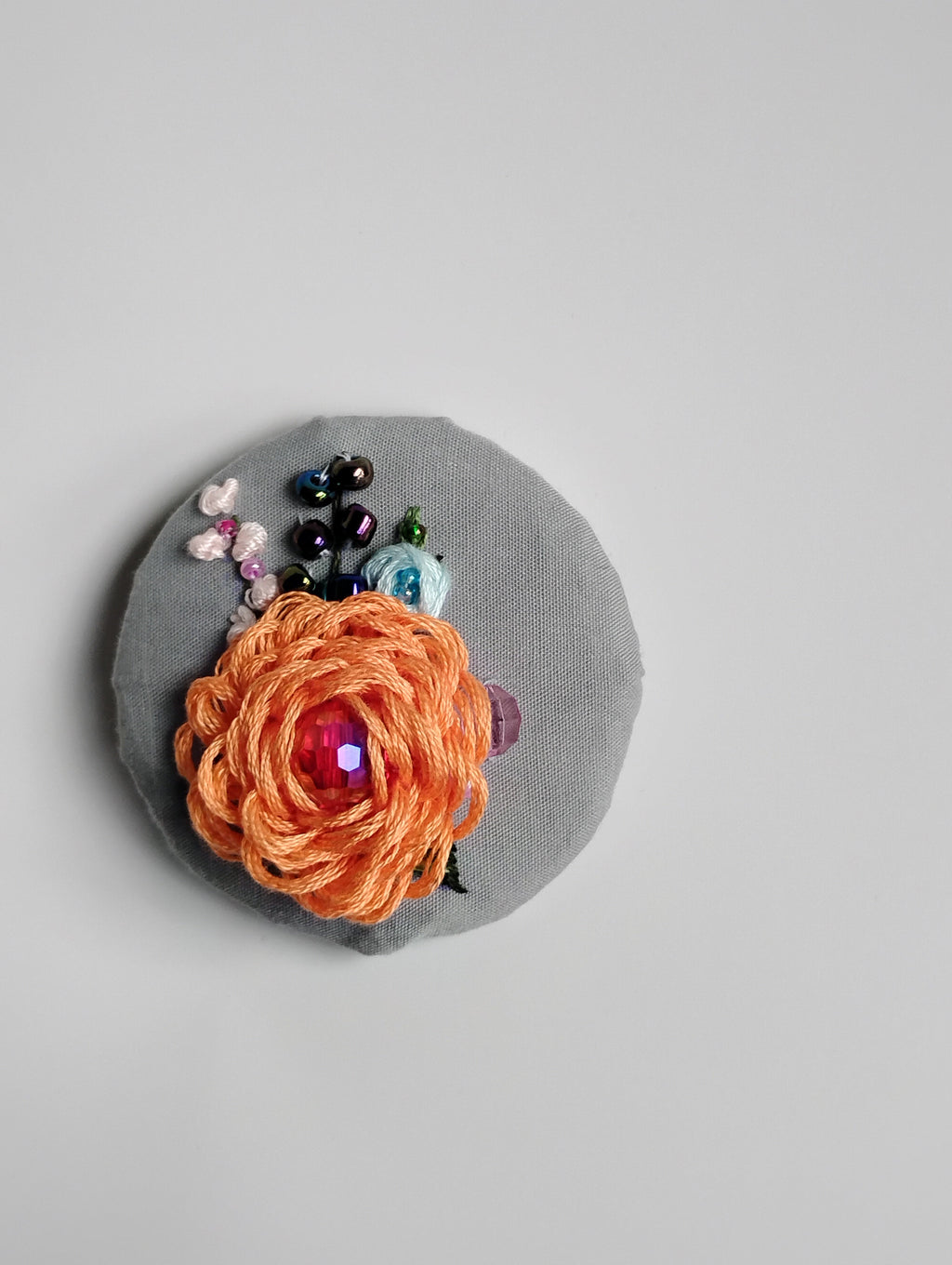 Decorative orange flower brooch on grey background