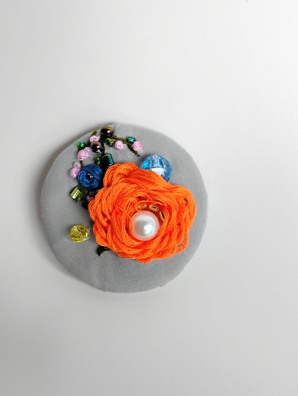 Decorative orange flower brooch on grey background