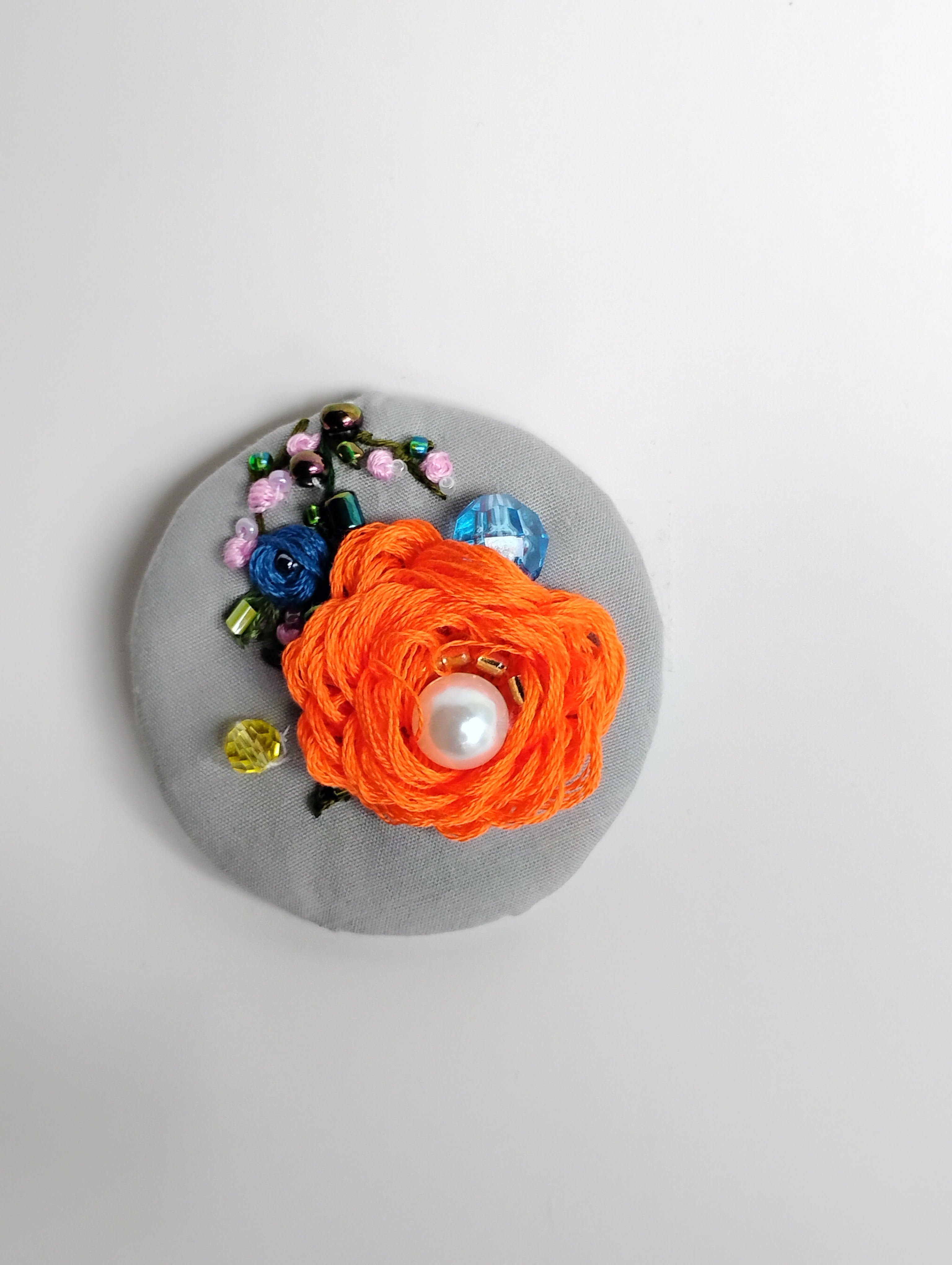 Decorative orange flower brooch on grey background