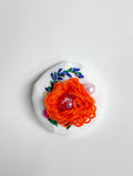 Decorative orange flower brooch on white textured background