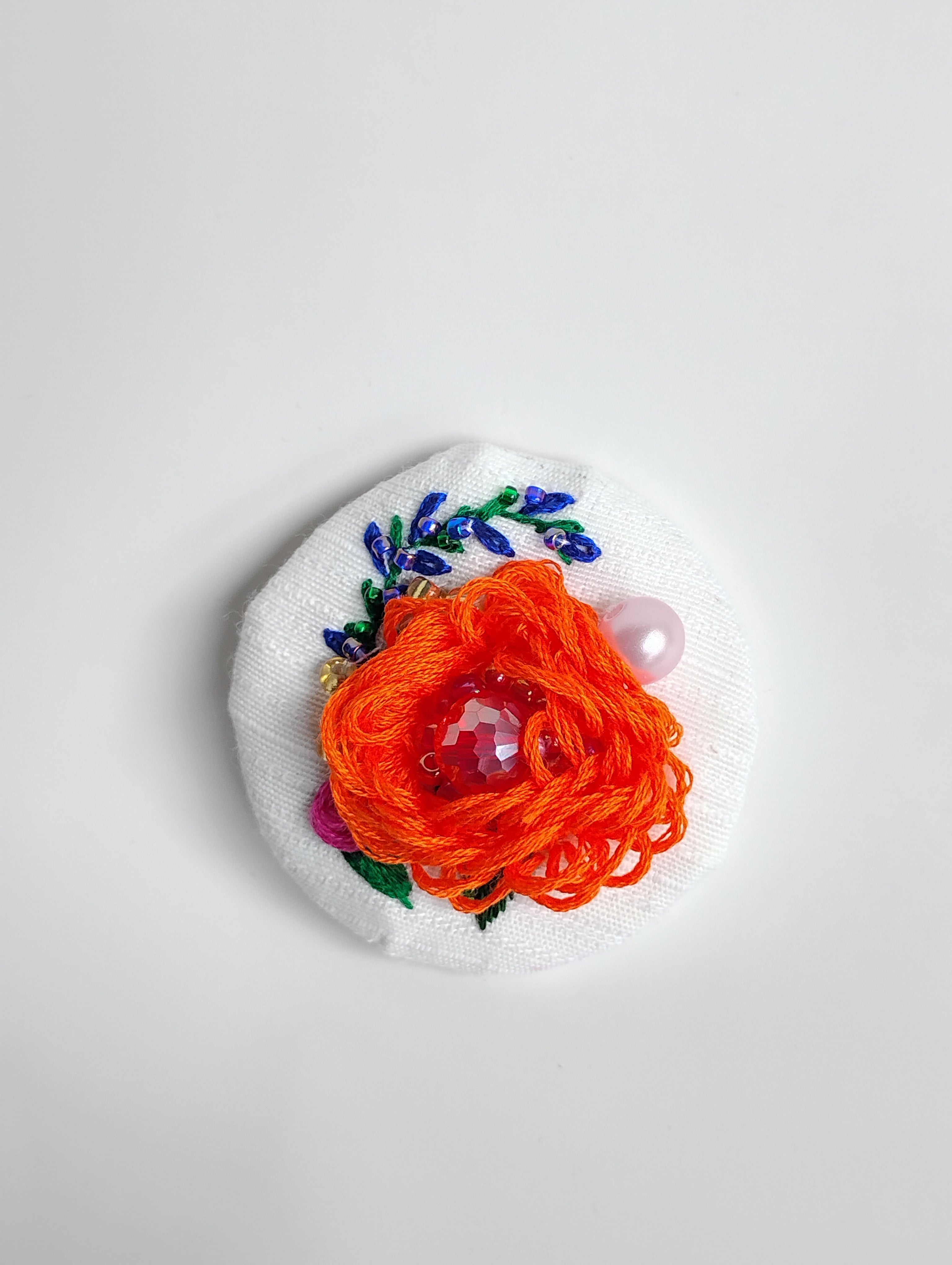 Decorative orange flower brooch on white textured background