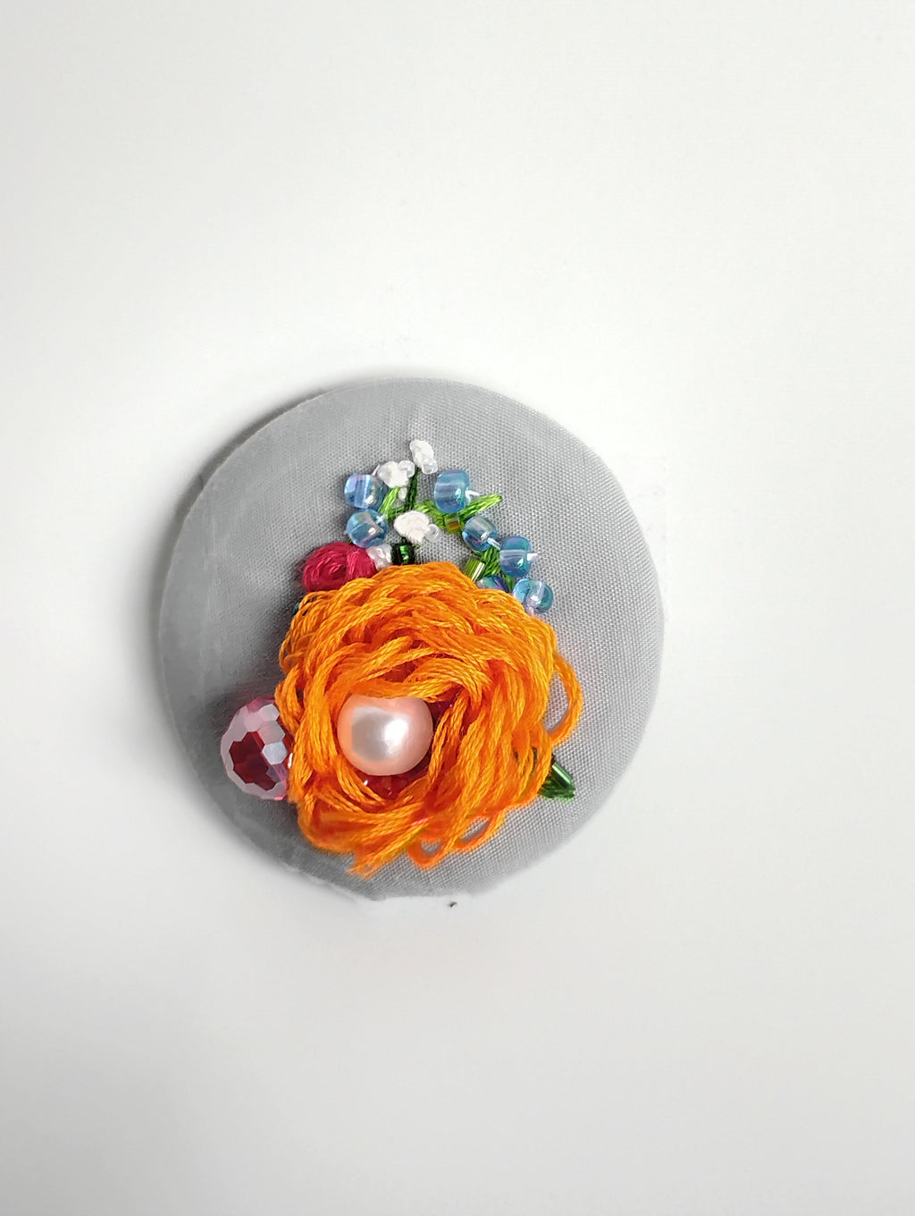 Decorative orange flower brooch on grey background
