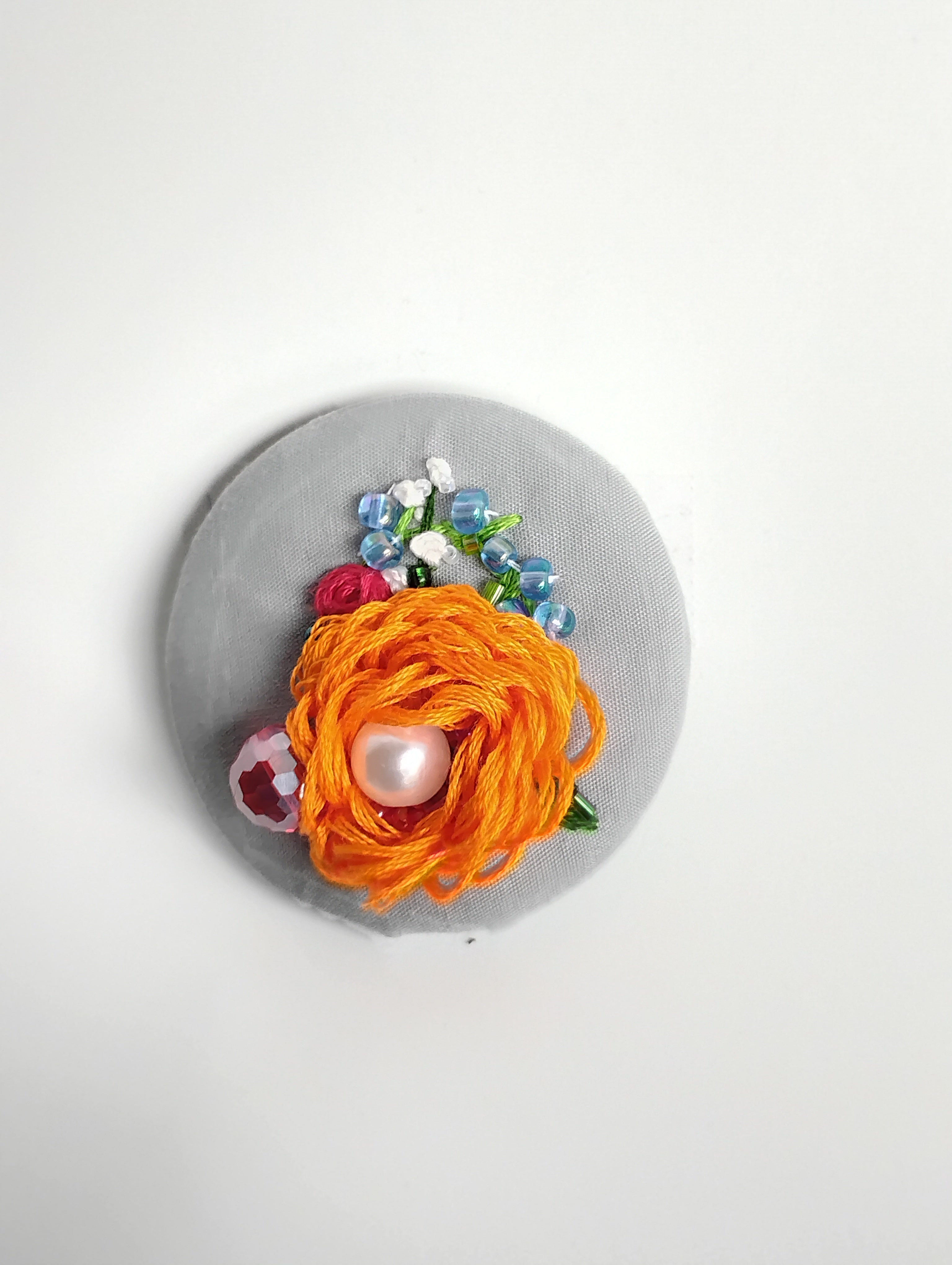 Decorative orange flower brooch on grey background
