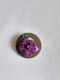 Decorative purple flower brooch on olive background
