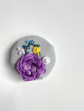 Decorative purple flower brooch on grey background