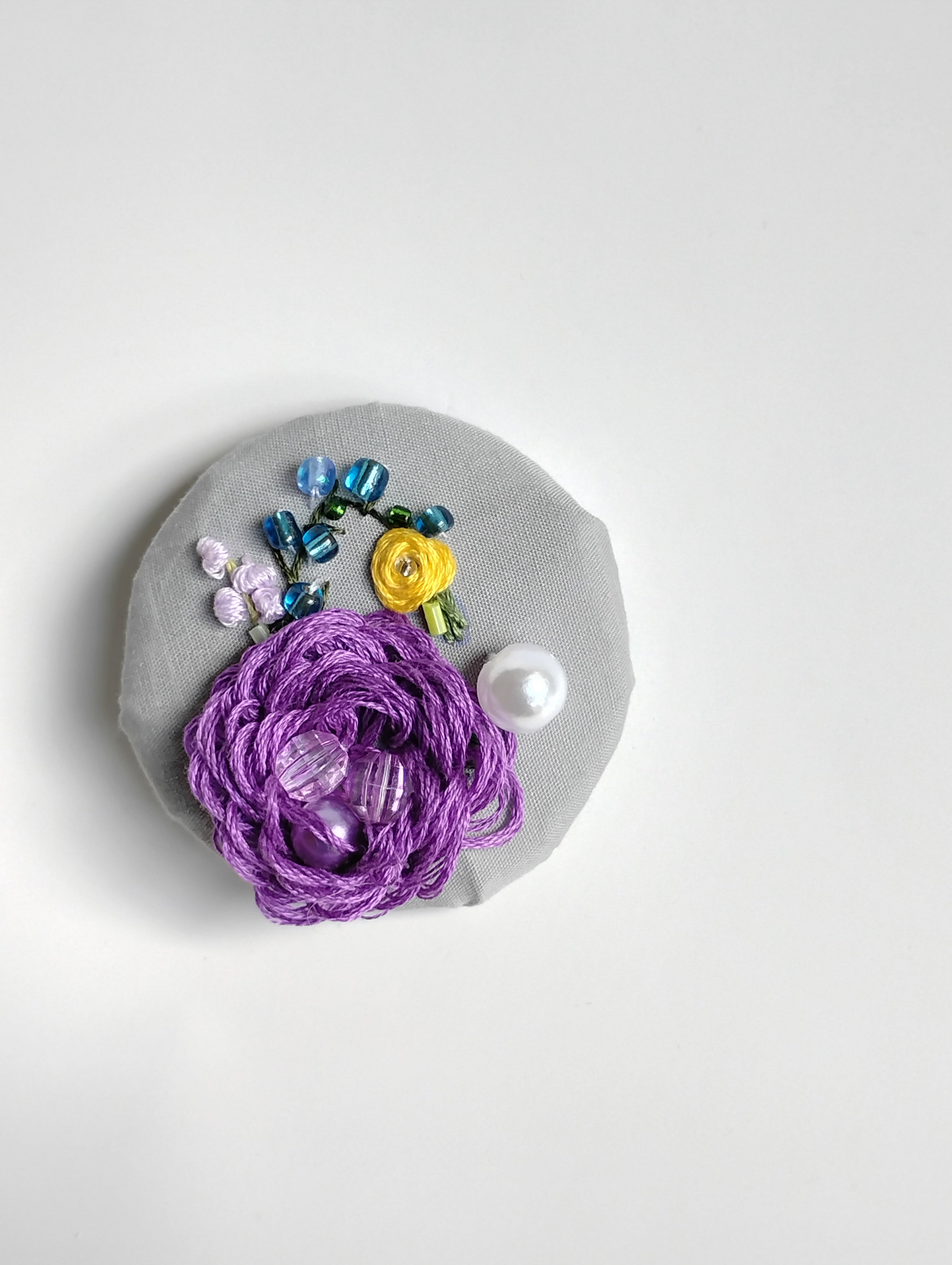 Decorative purple flower brooch on grey background