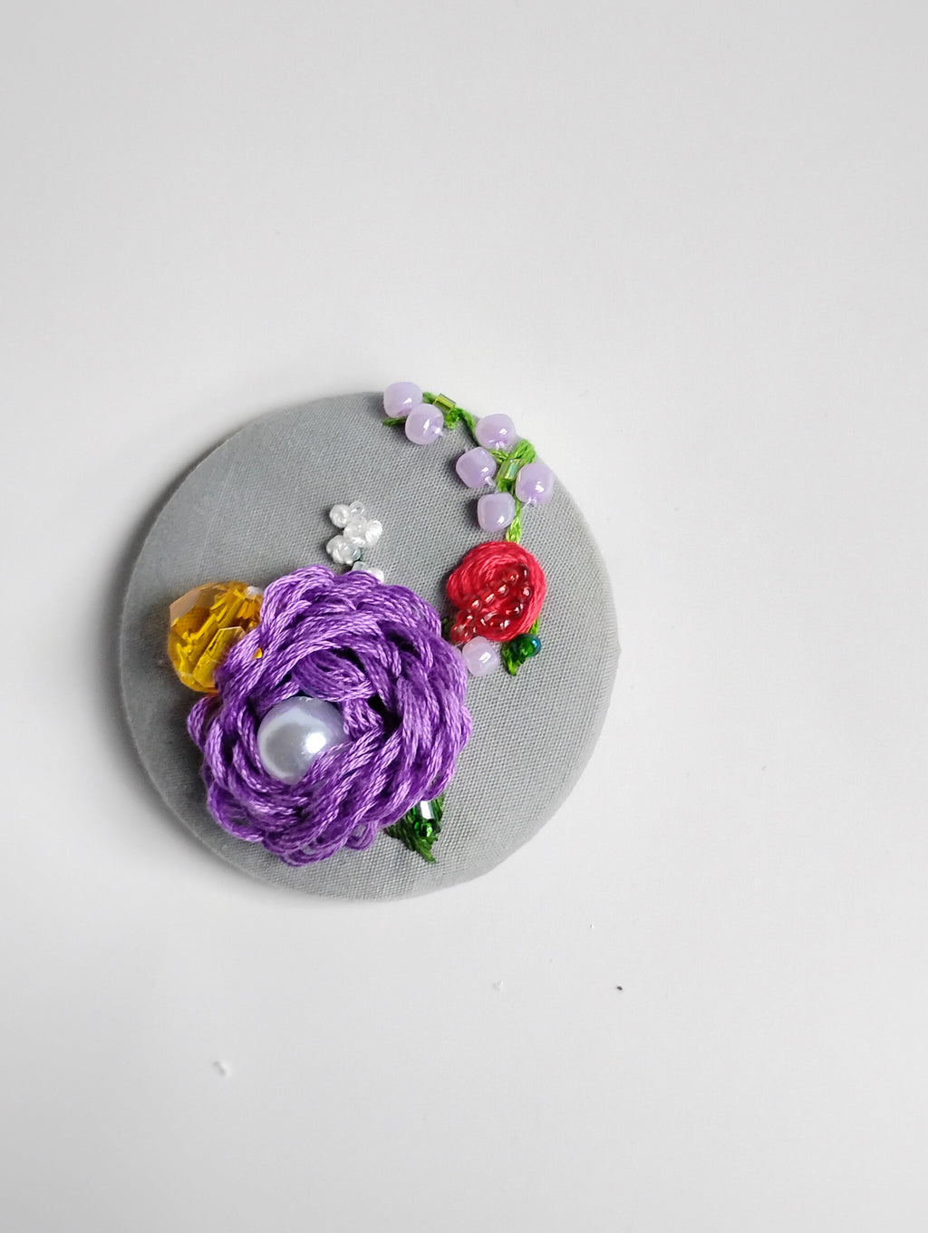 Decorative purple flower brooch on grey background