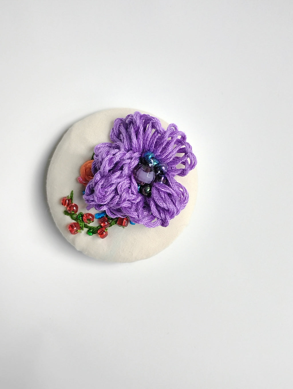 Decorative purple flower brooch on cream background