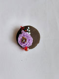 Decorative purple flower brooch on olive background