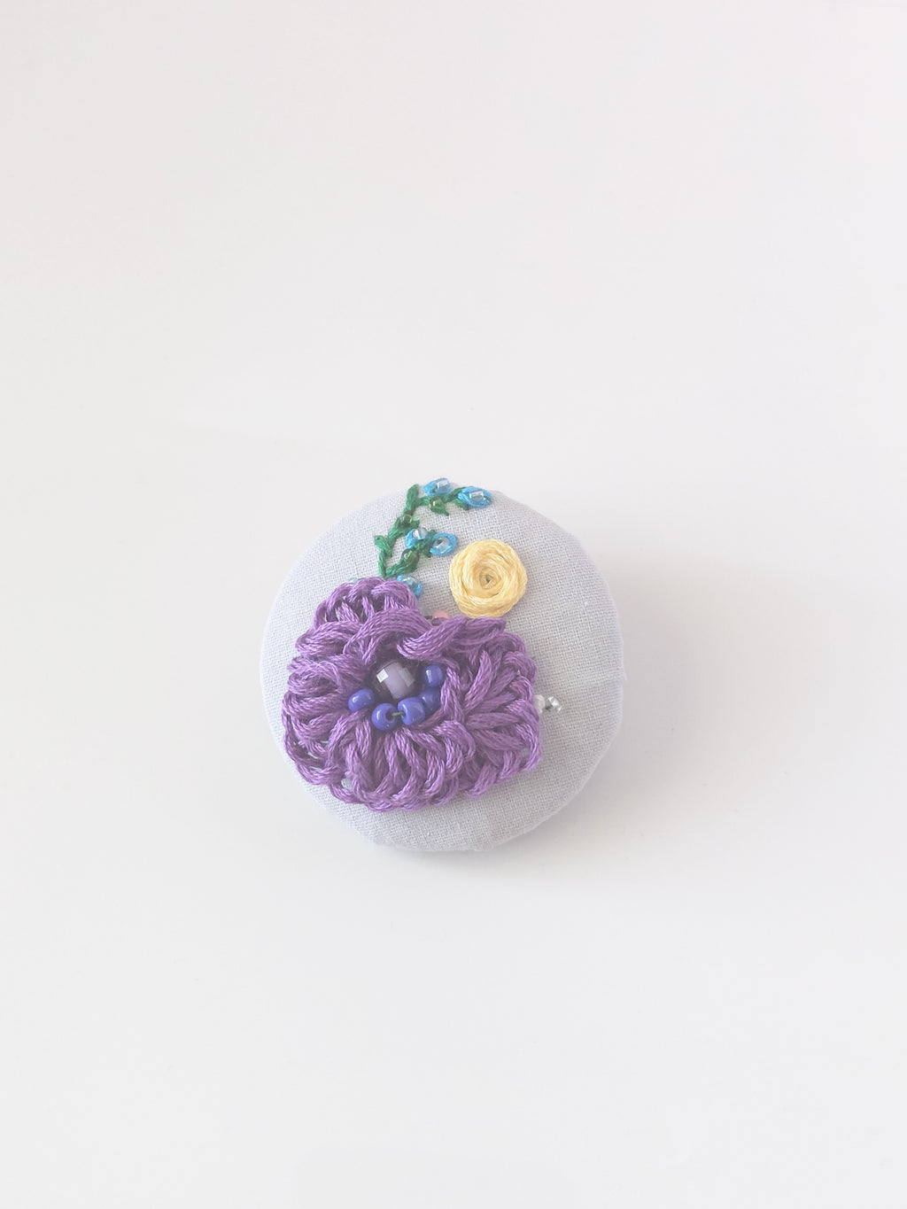 Decorative purple flower brooch on grey background