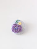 Decorative purple flower brooch on grey background
