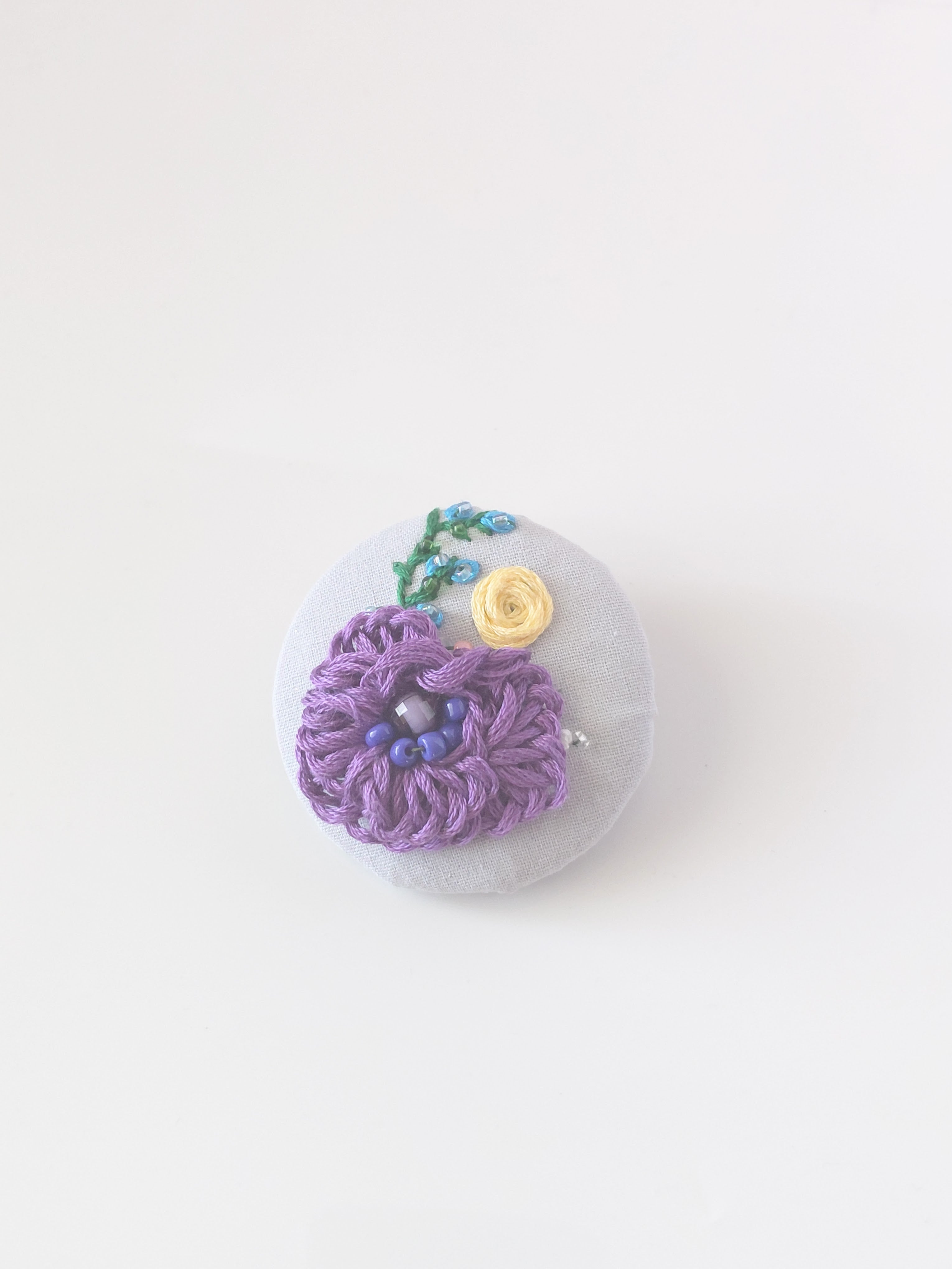 Decorative purple flower brooch on grey background