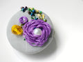 Decorative purple flower brooch on grey background