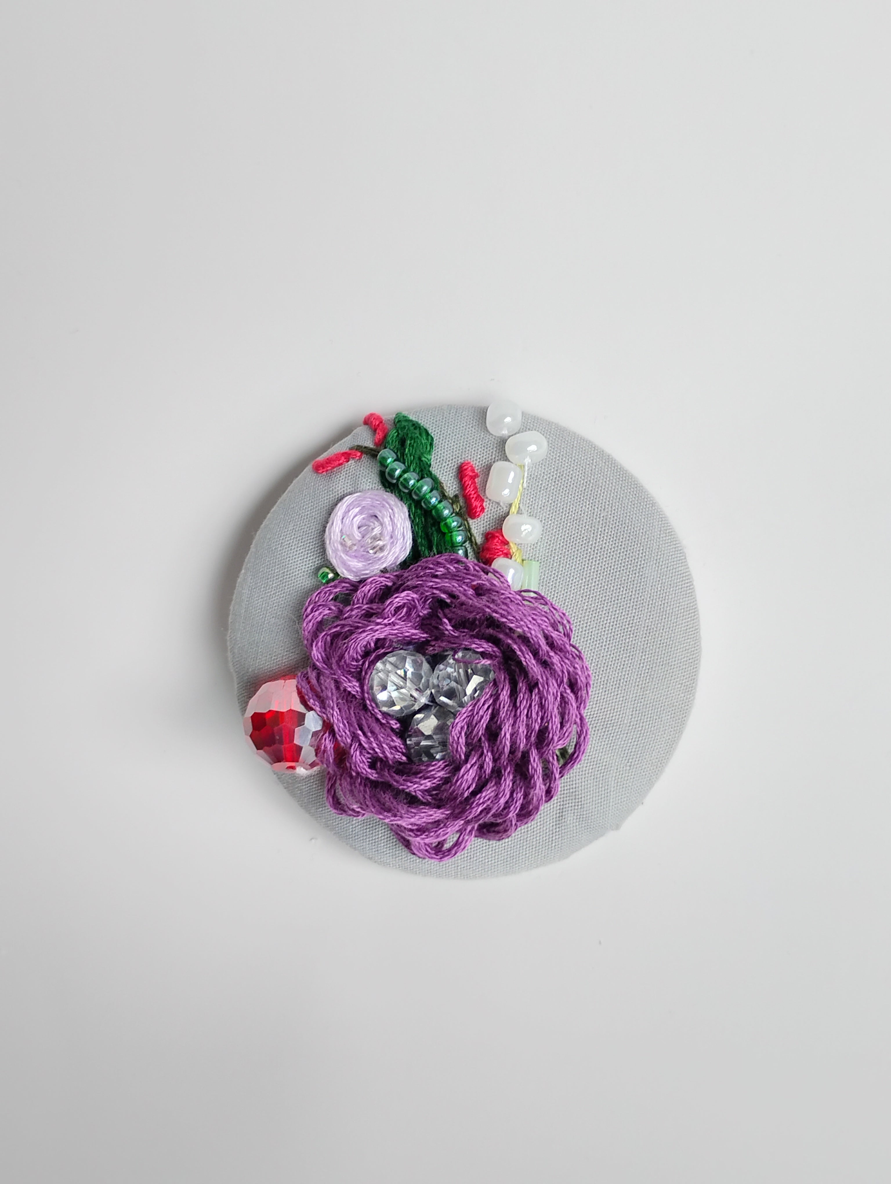 Decorative purple flower brooch on grey background