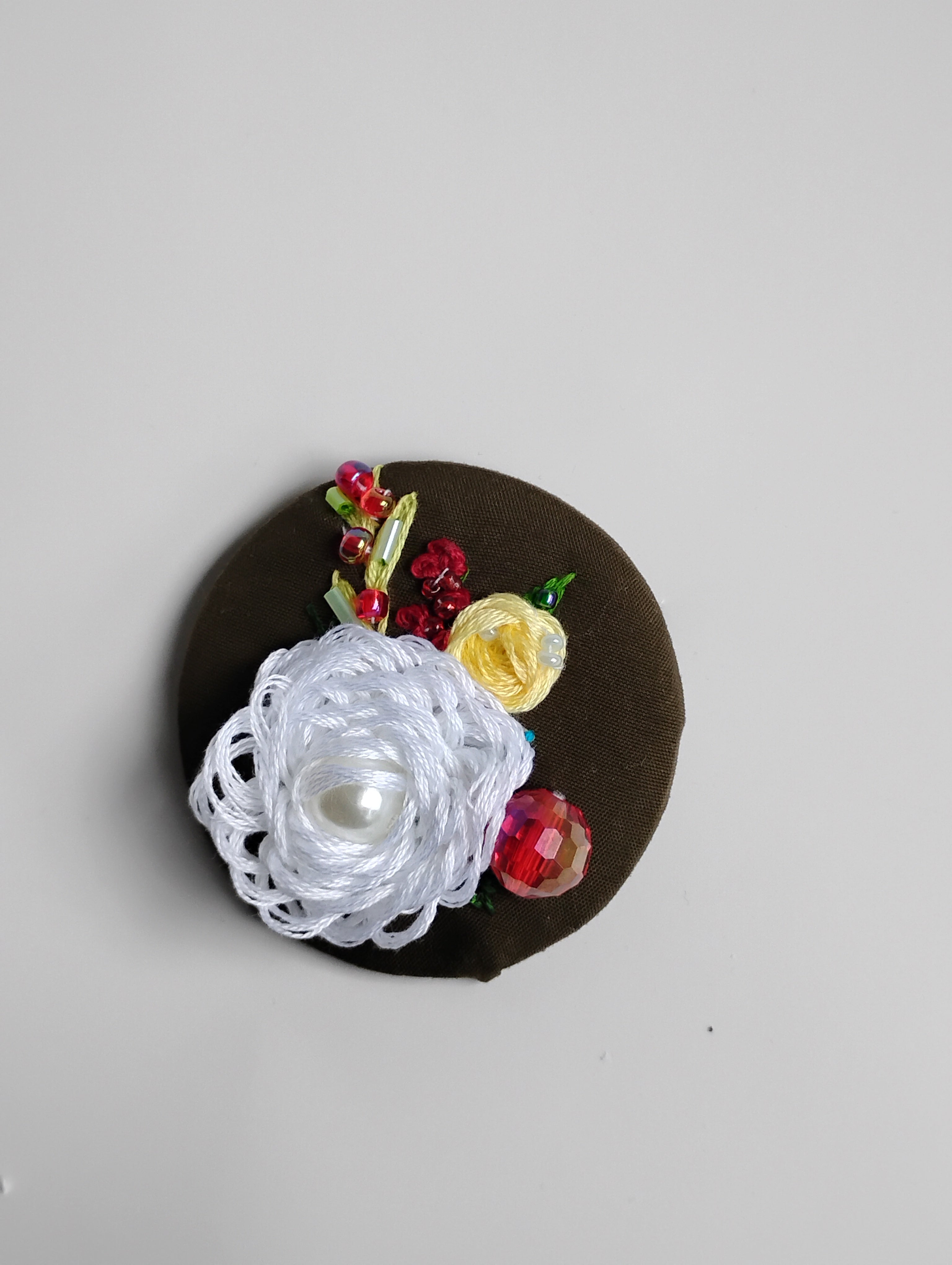 Decorative white flower brooch on olive background