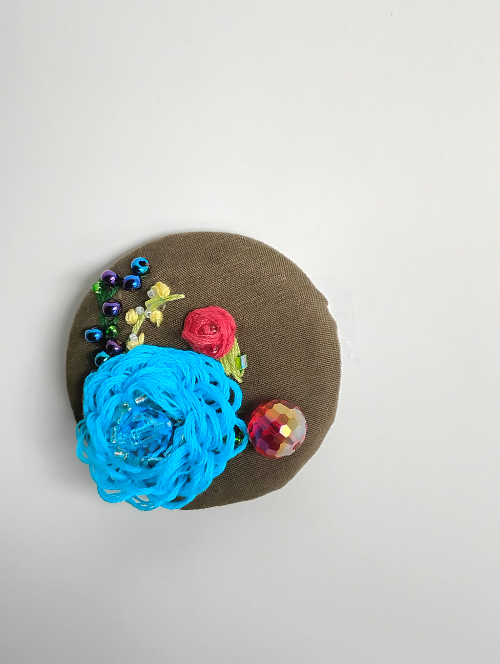 Decorative turquoise flower brooch on olive background