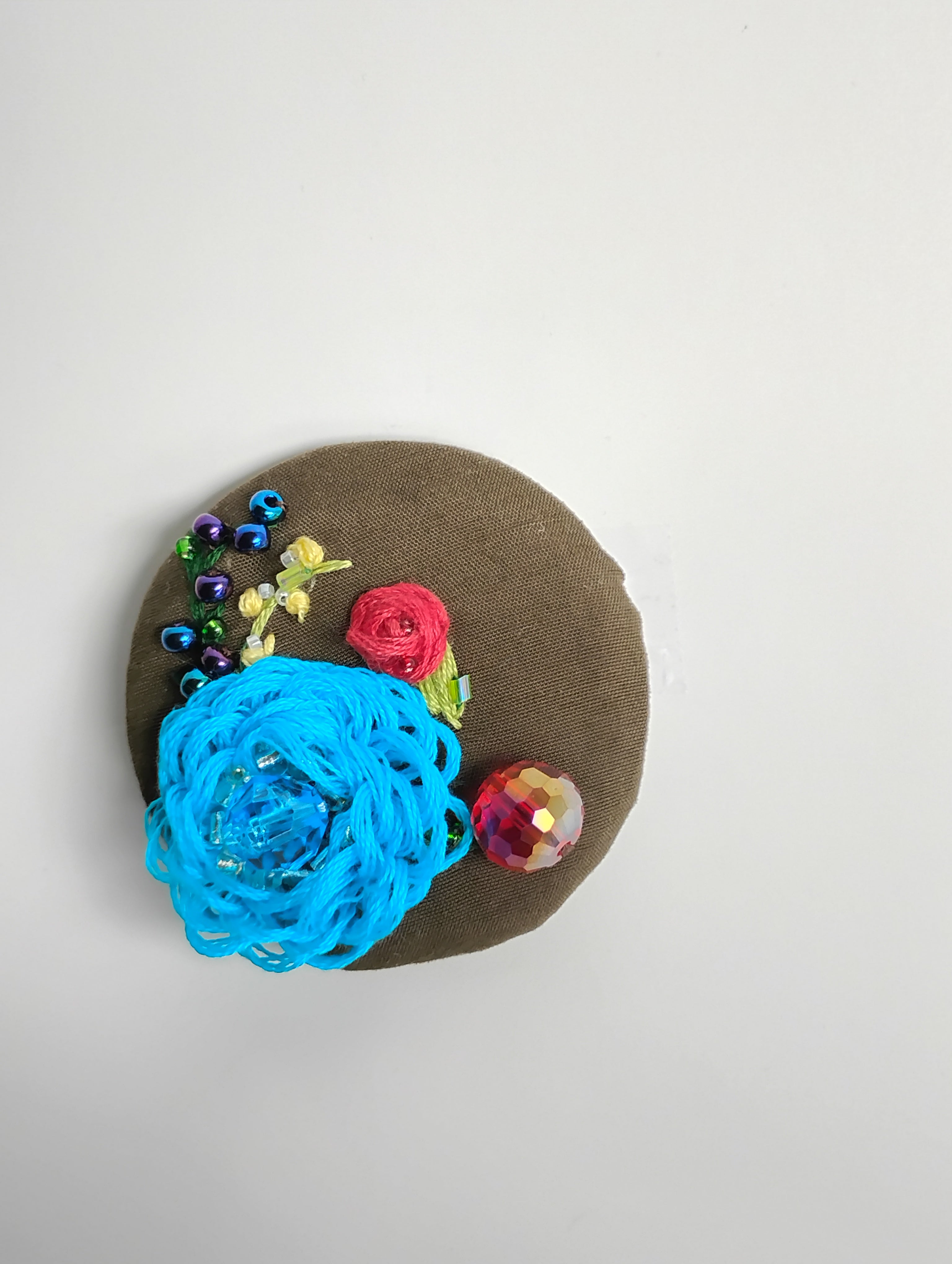 Decorative turquoise flower brooch on olive background