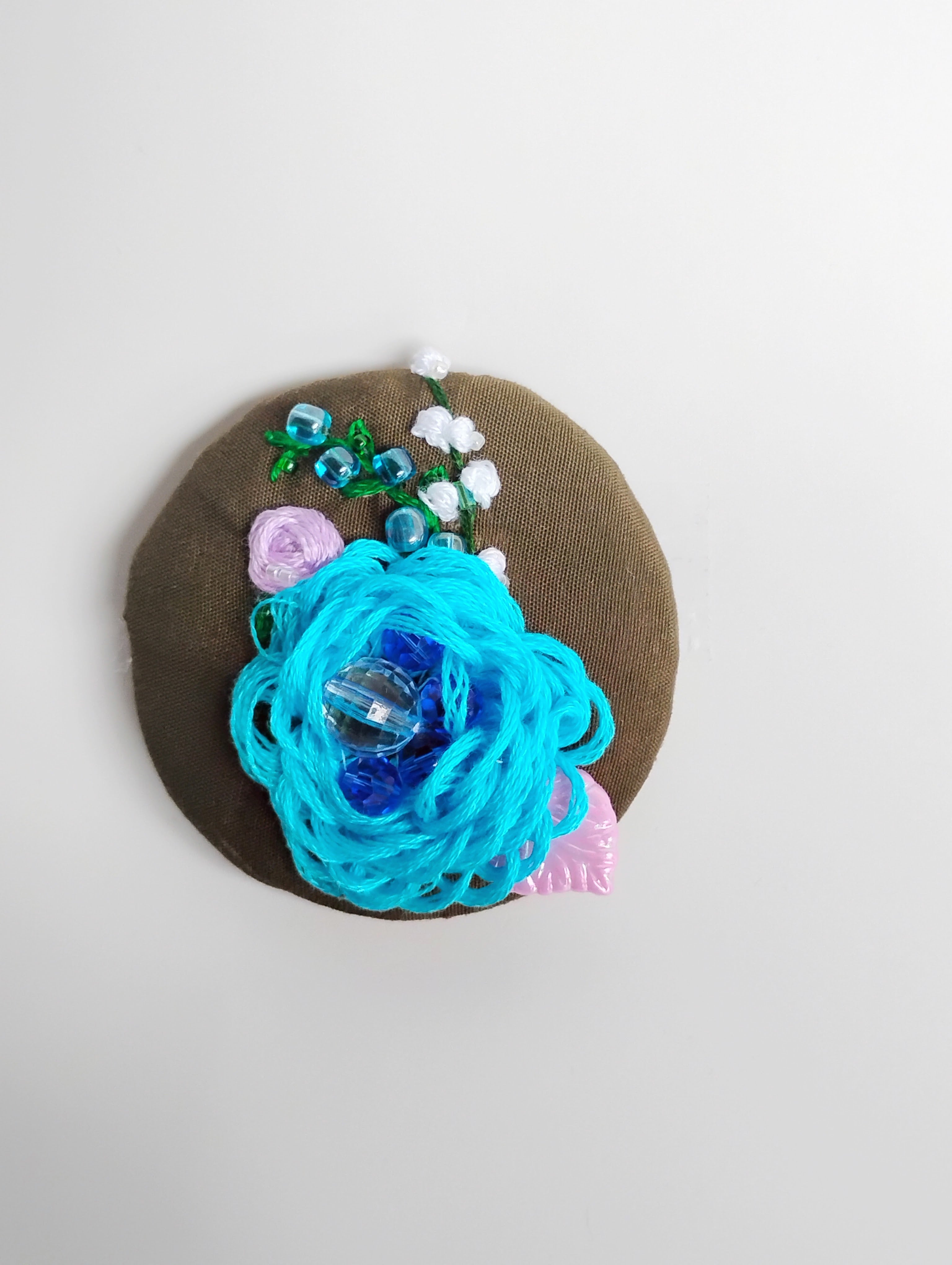 Decorative turquoise flower brooch on olive background