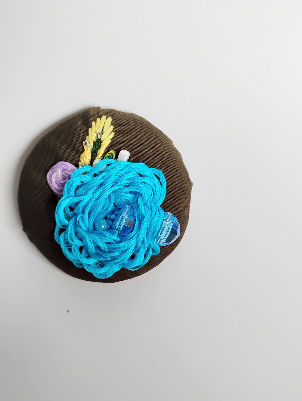 Decorative turquoise flower brooch on olive background