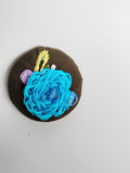 Decorative turquoise flower brooch on olive background