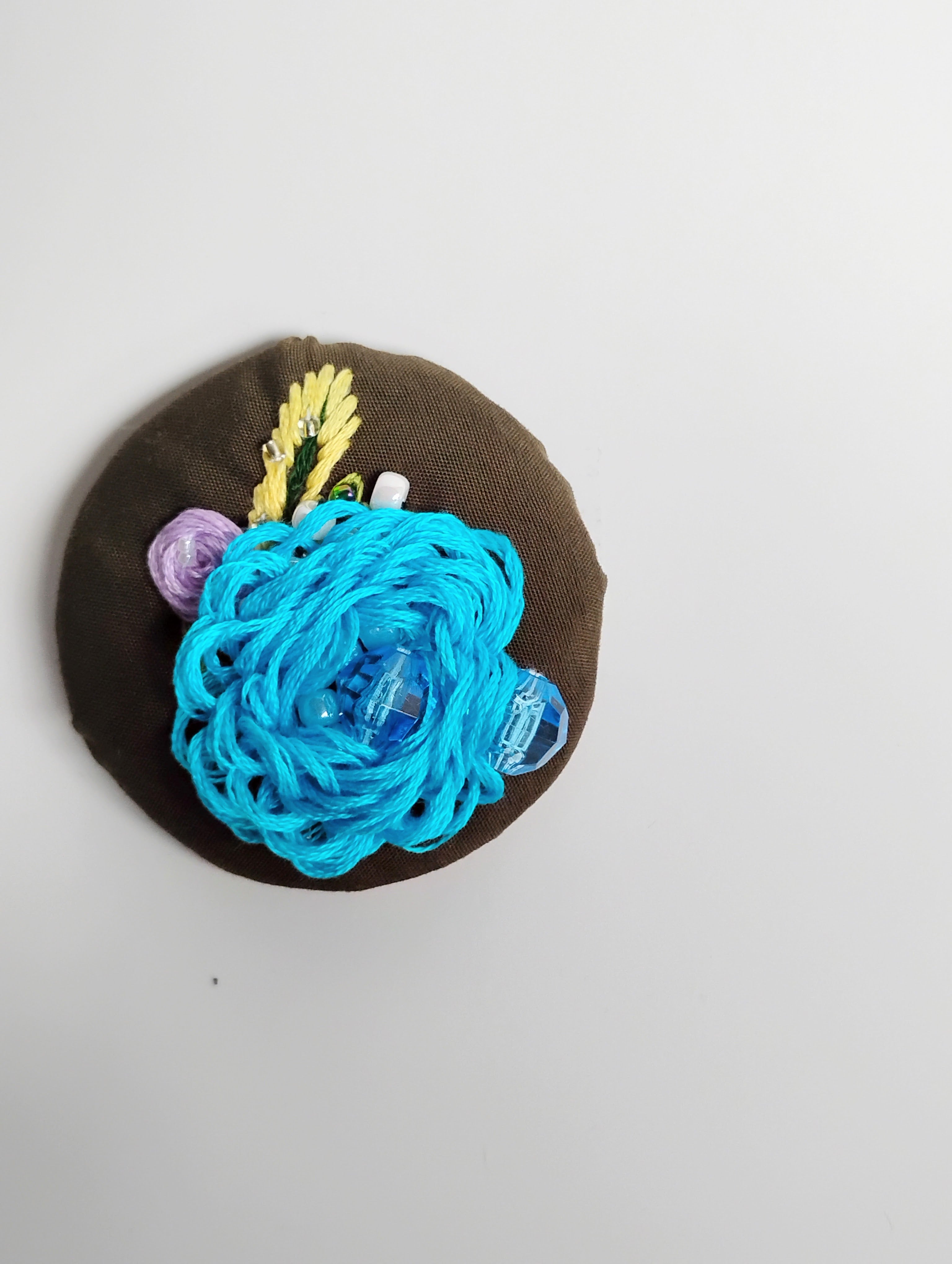 Decorative turquoise flower brooch on olive background