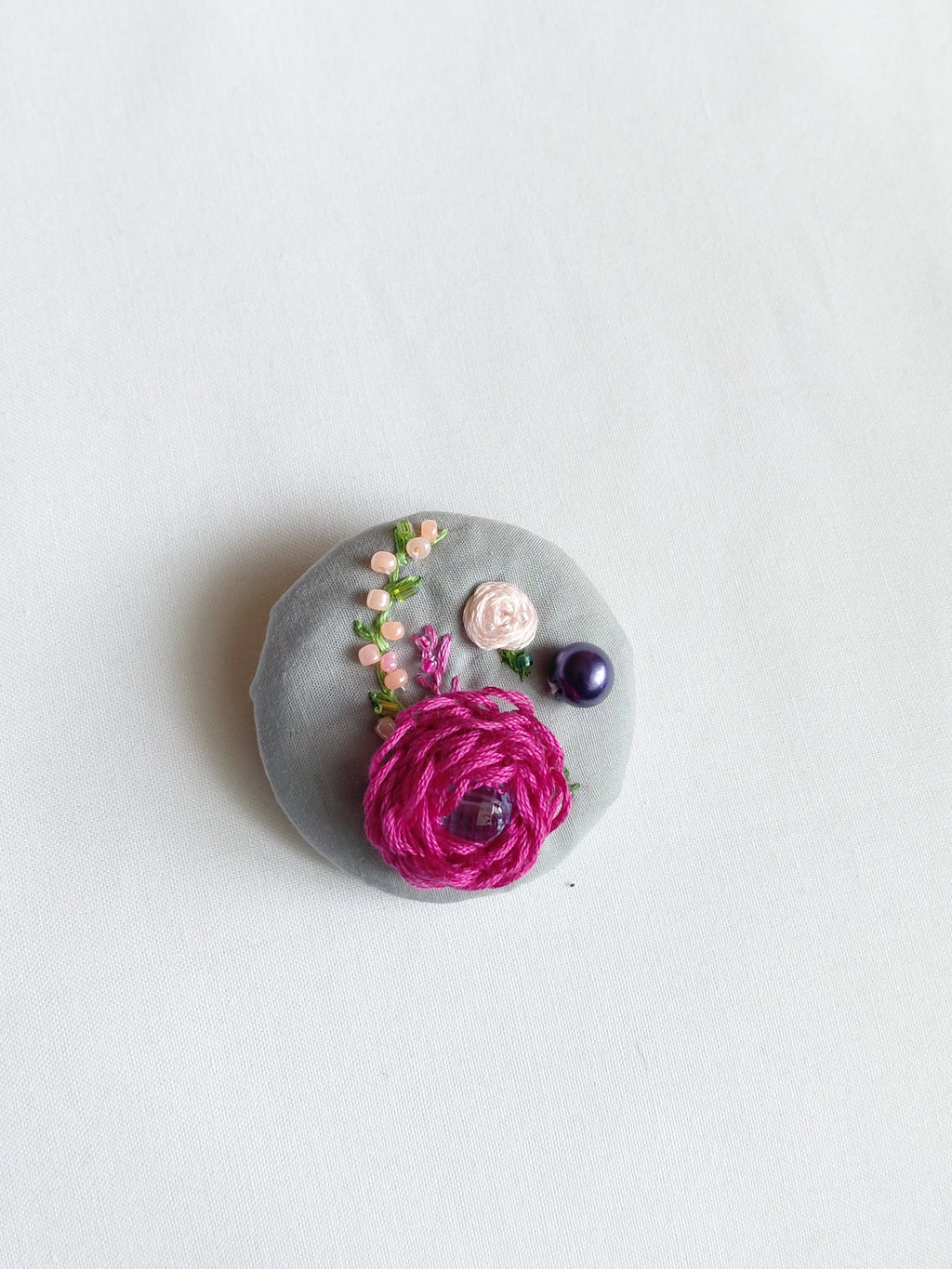 Decorative fuschia flower brooch on grey background