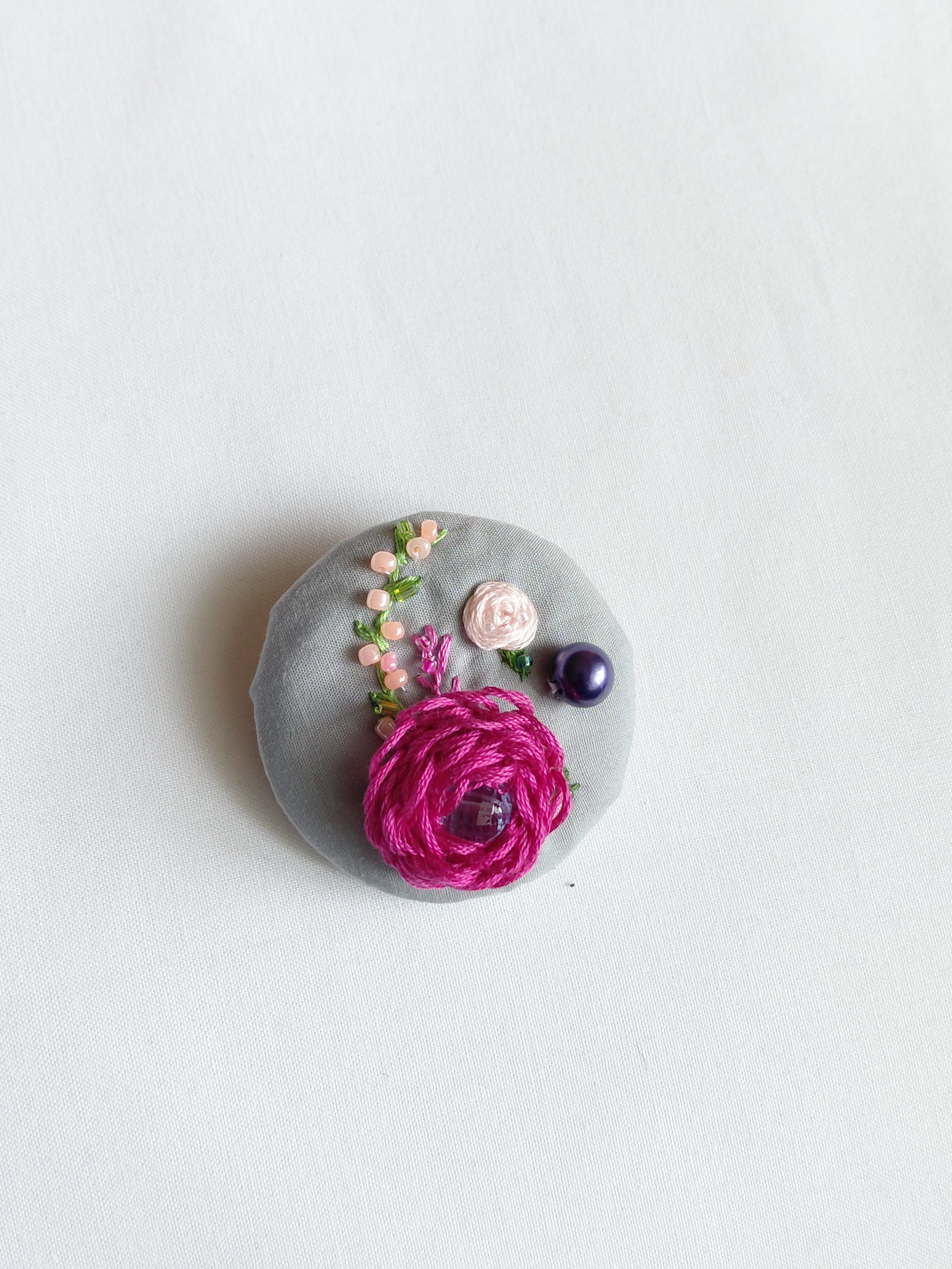 Decorative fuschia flower brooch on grey background