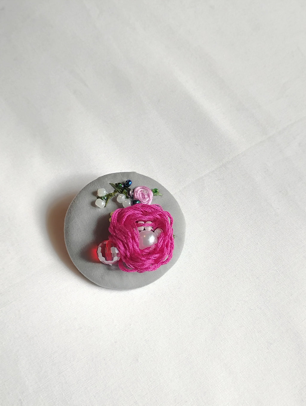 Decorative fuschia flower brooch on grey background
