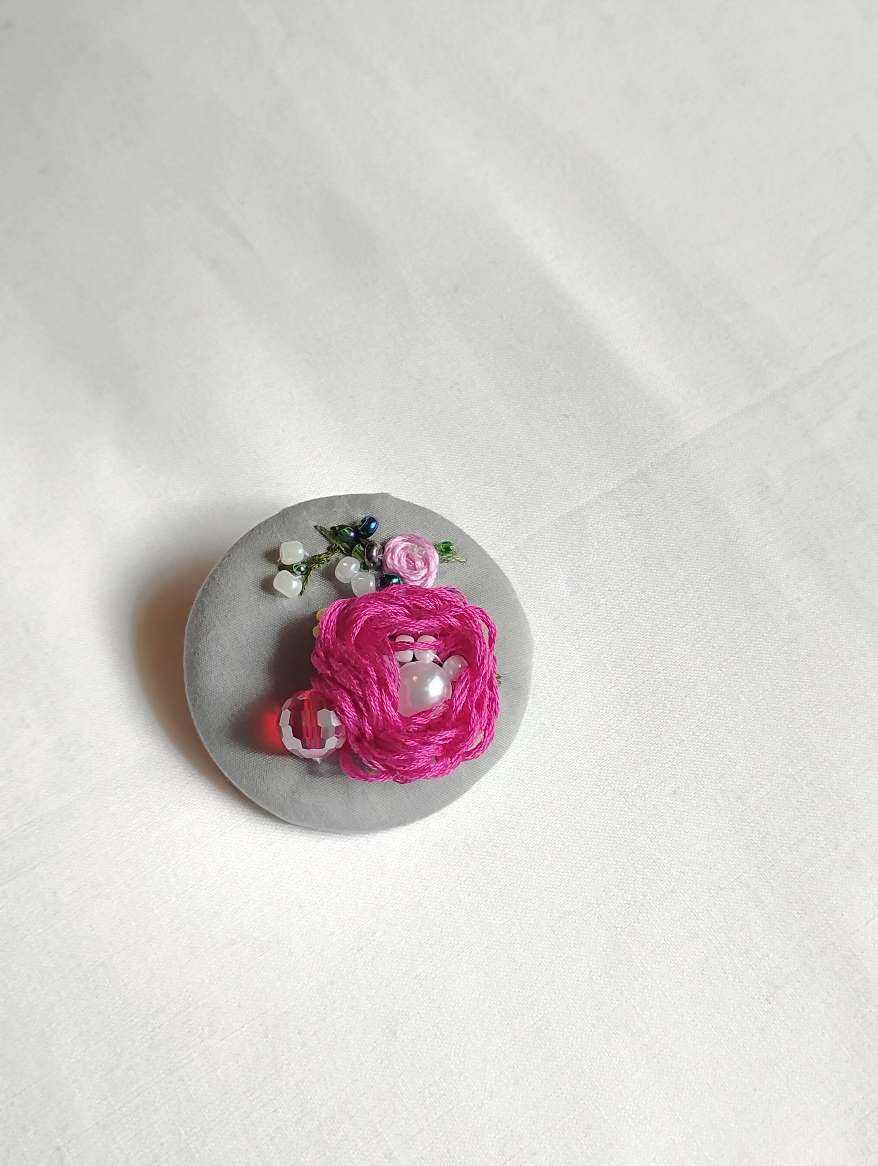 Decorative fuschia flower brooch on grey background