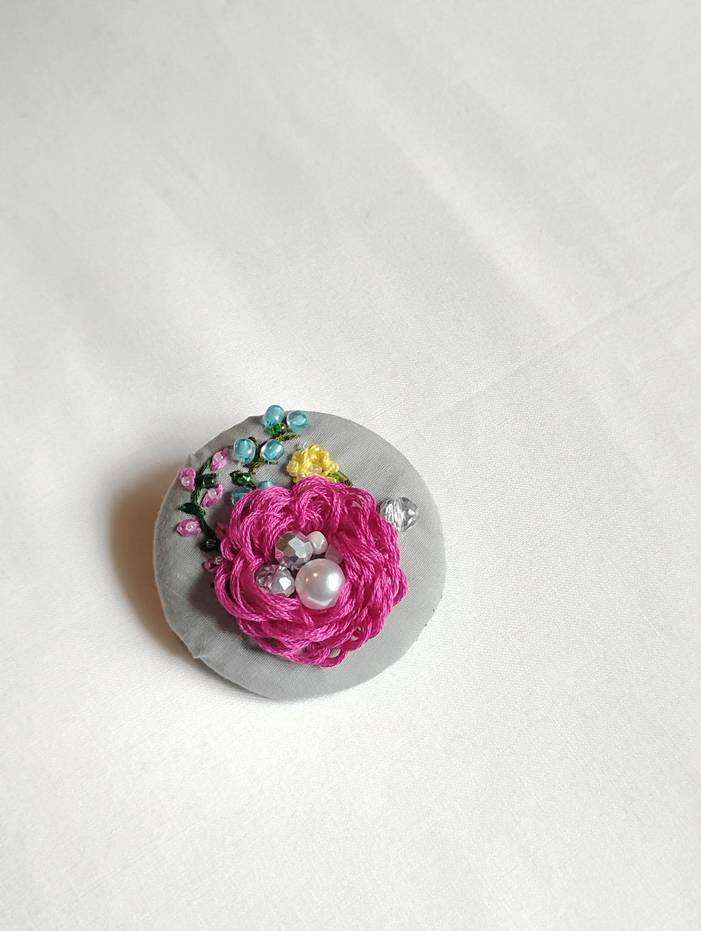 Decorative fuschia flower brooch on grey background