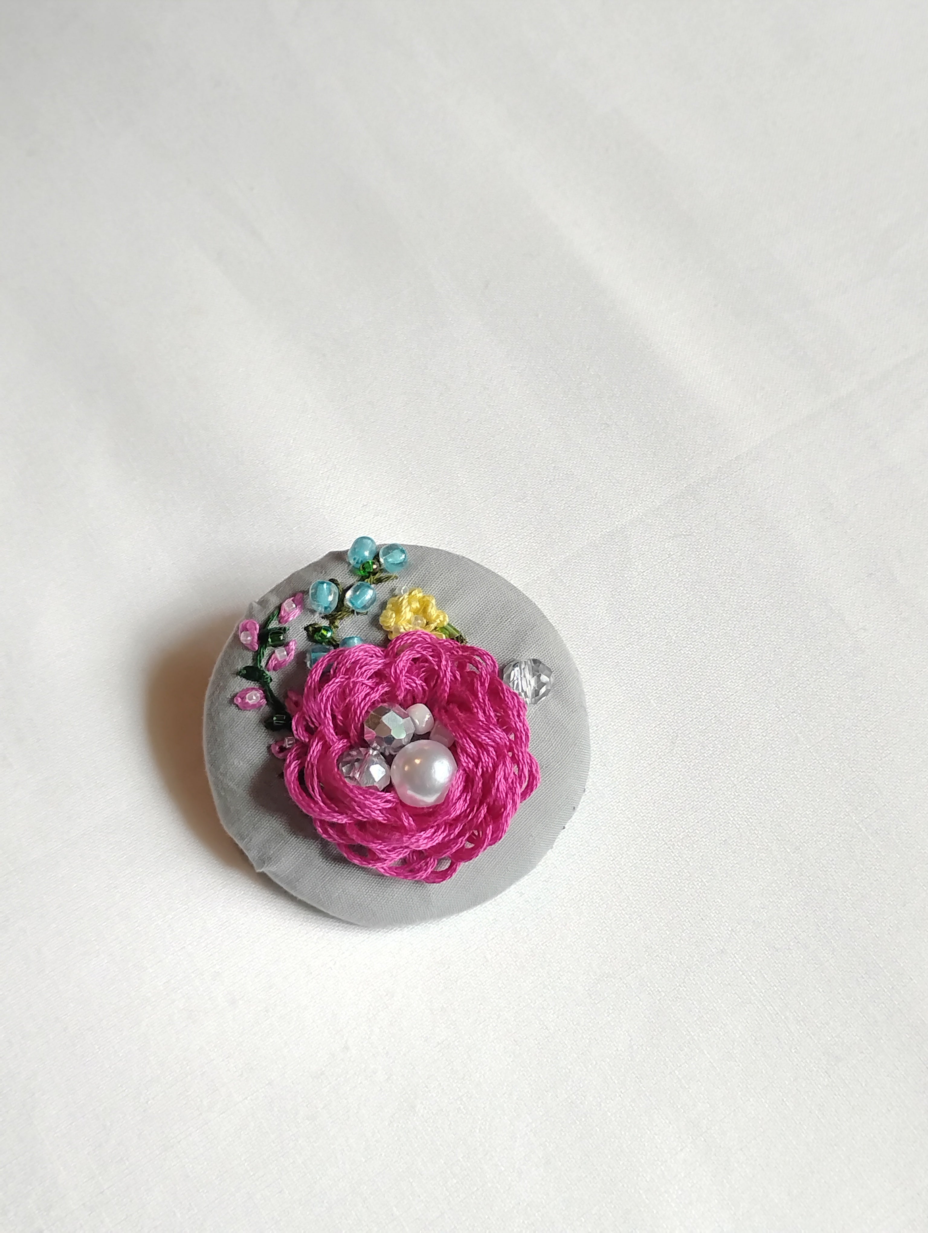 Decorative fuschia flower brooch on grey background