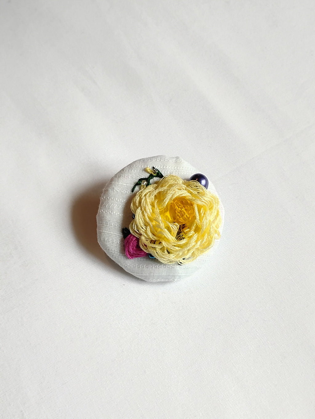 Decorative yellow flower brooch on white textured background