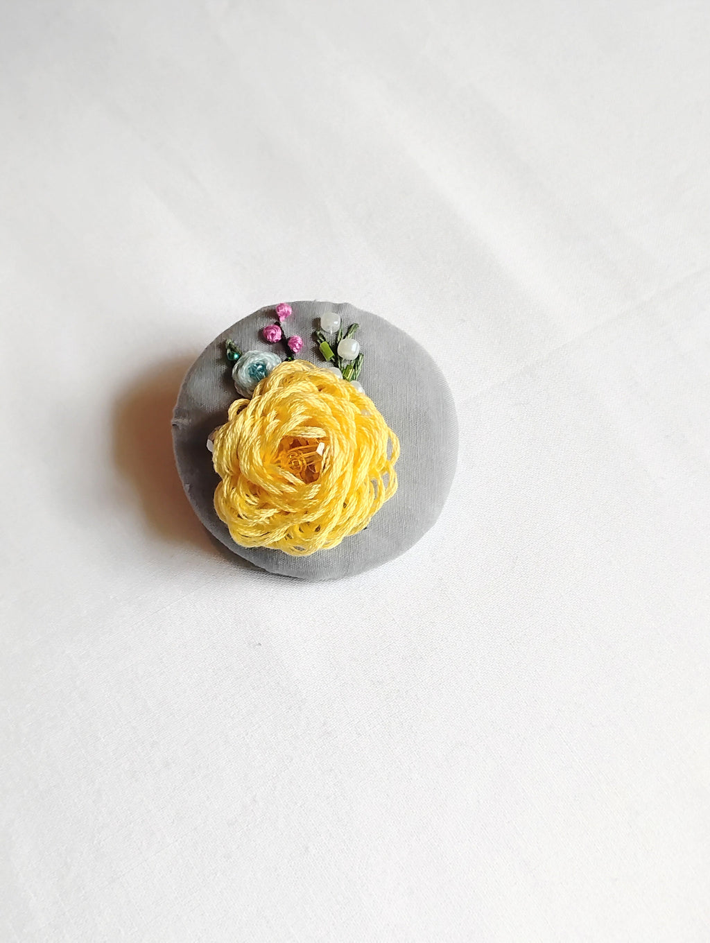 Decorative yellow flower brooch on grey background