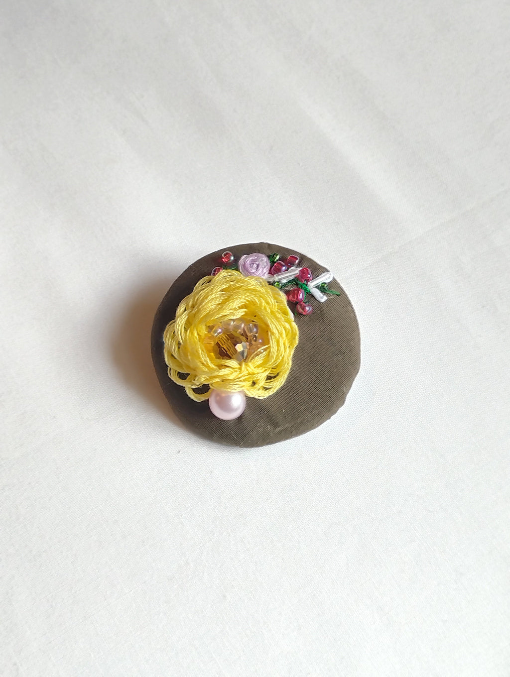 Decorative yellow flower brooch on olive background