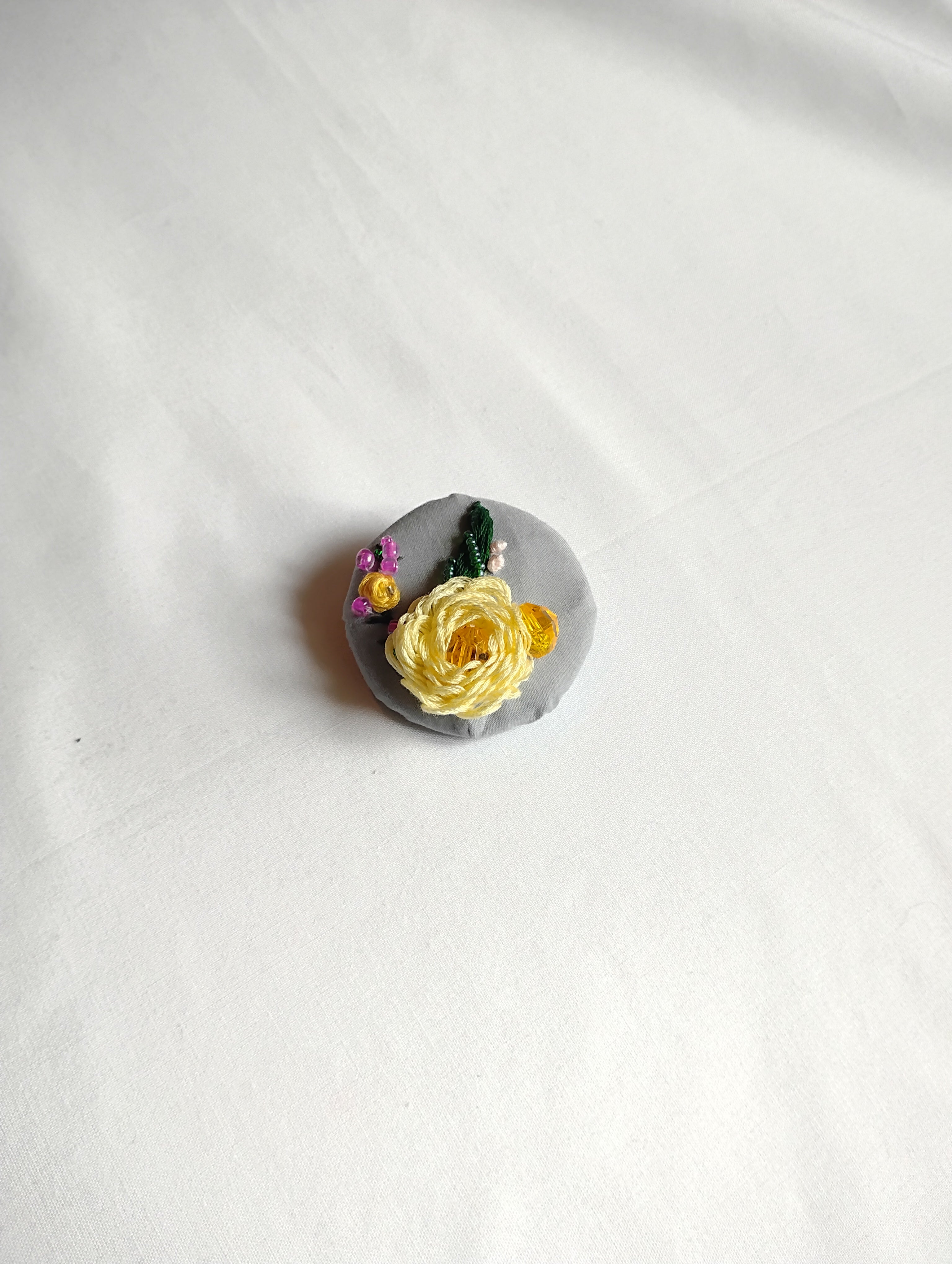 Decorative yellow flower brooch on grey background