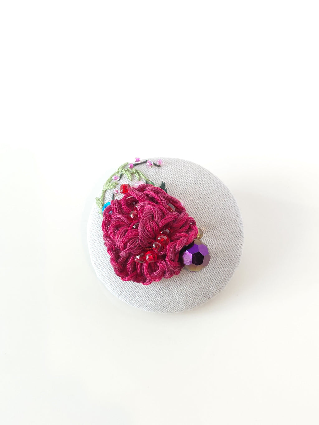 Decorative burgundy flower brooch on grey background